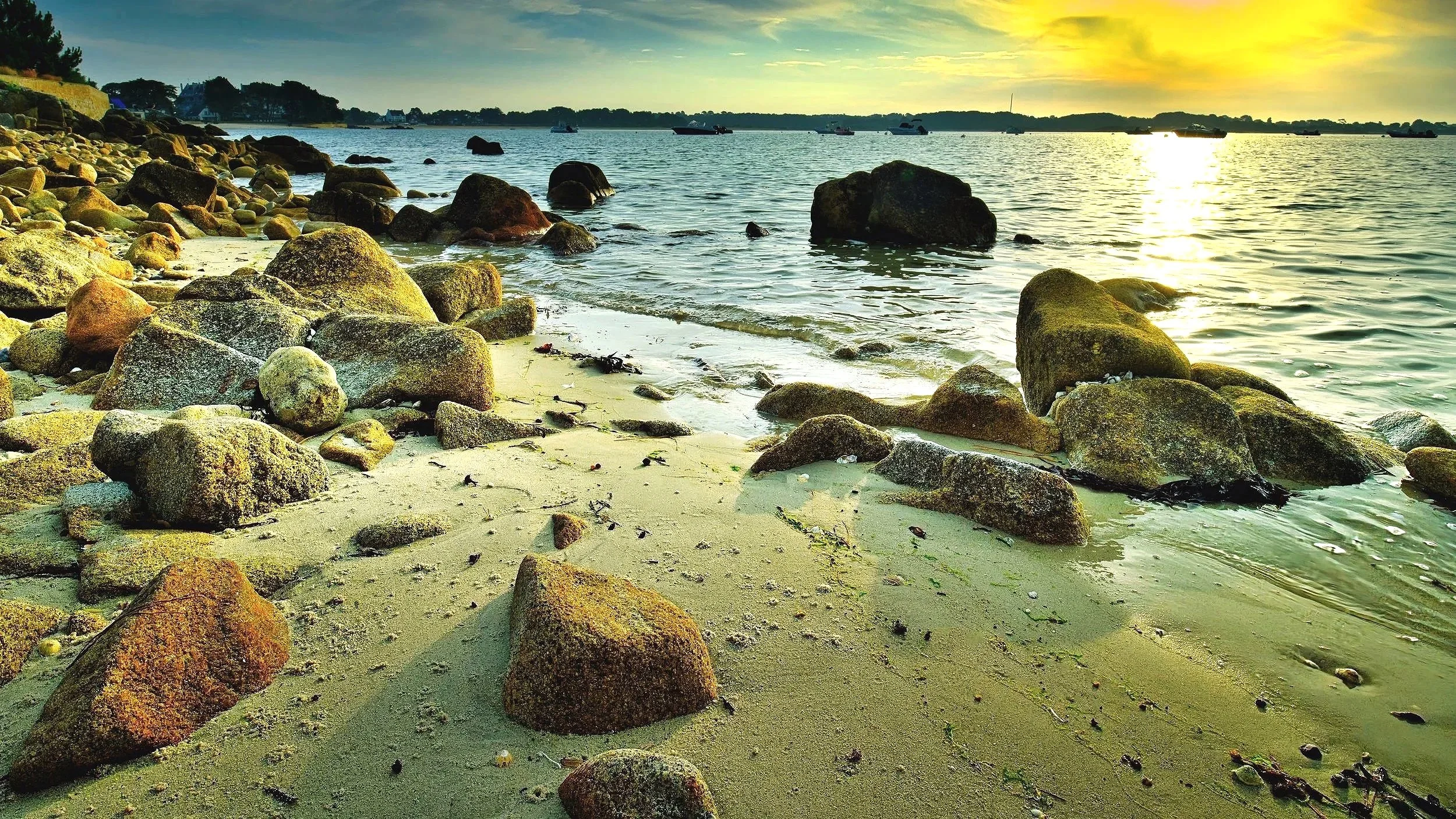 "Bolders on Beaumer Beach" Taken as the sun spills onto Quiberon Bay, Brittany, France. Warms tones lighting up the tops of bolders in the forground as they are lapped by the receding tide.  