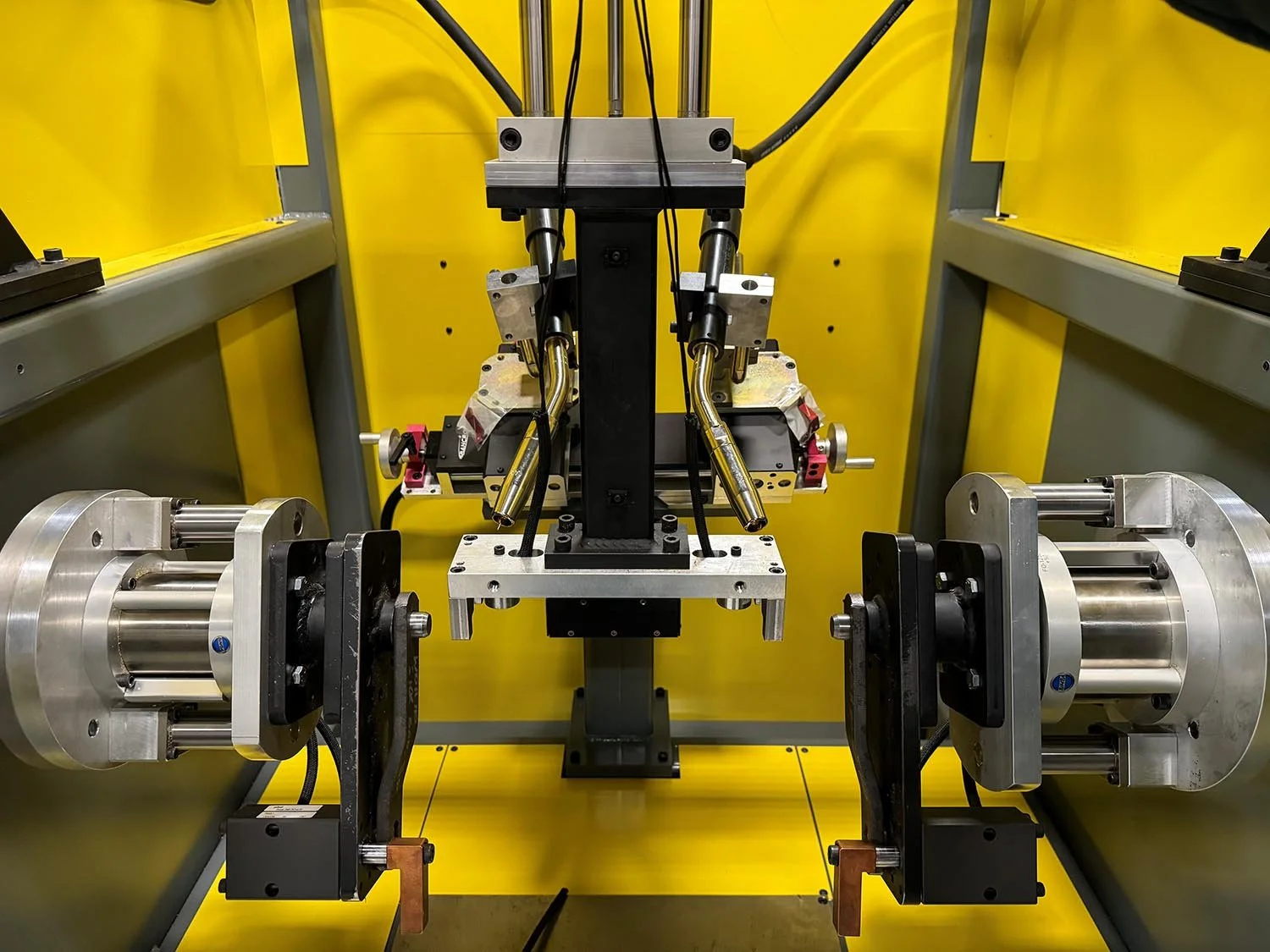 Industrial machinery setup with metal rods, electronic components, and precise alignment within a yellow enclosure.