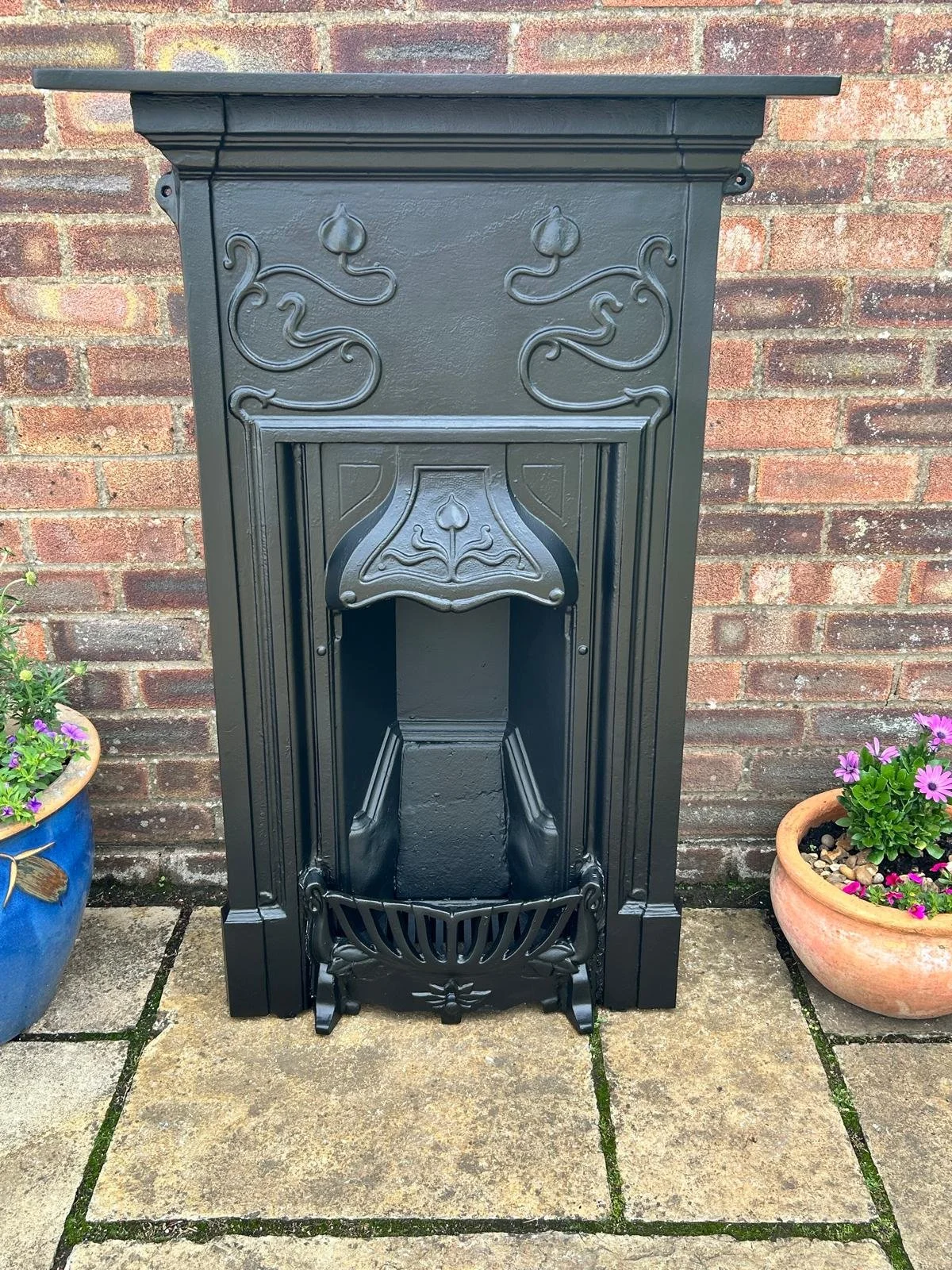 Black vintage cast-iron fireplace with decorative patterns. This Art Nouveau style vintage fireplace will add charm to any room in your home.