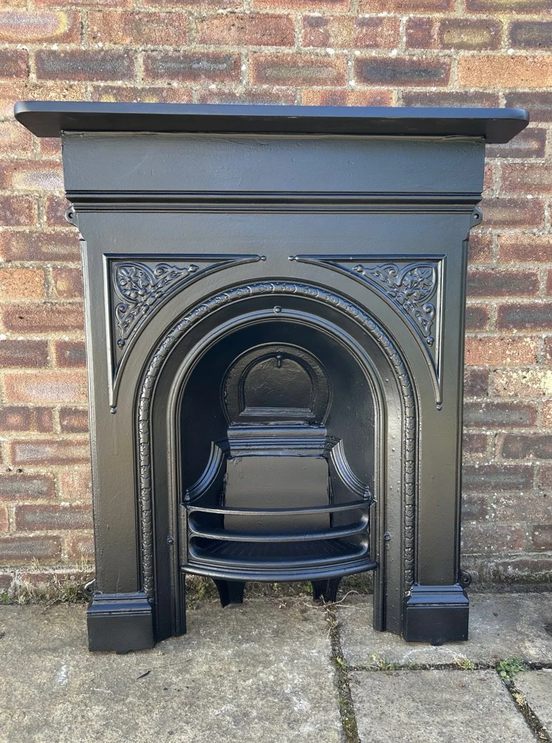 Black cast iron fireplace with ornate decorative detailing. Restored in the UK, ready to become the centre piece of any home.