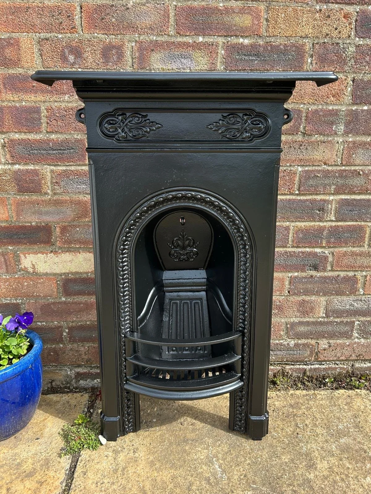 A black decorative cast iron fireplace, lovingly restored by hand with ornate detailing, perfect to add vintage charm to any room in your home.
