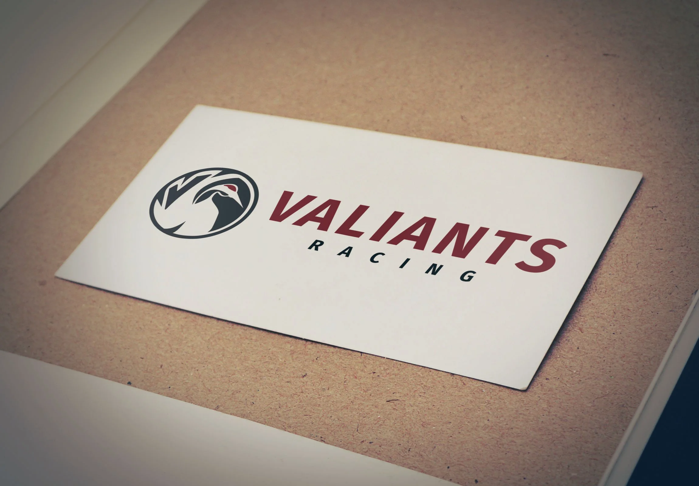 A paper with a logo of a bird and the text 'Valiant Racing' on a brown surface.