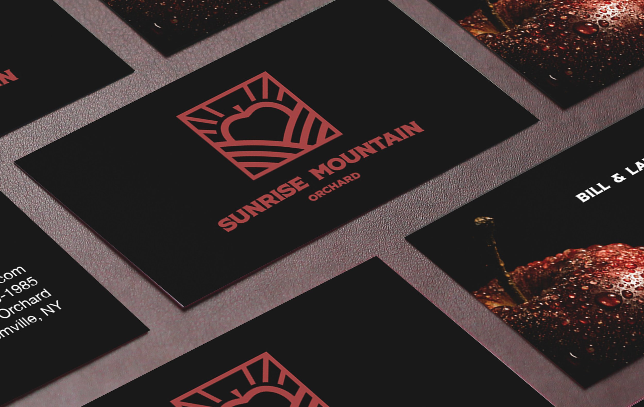 Close-up of black cards with red and white text, including a card with a mountain logo and the words 'Sunrise Mountain Orchard.'