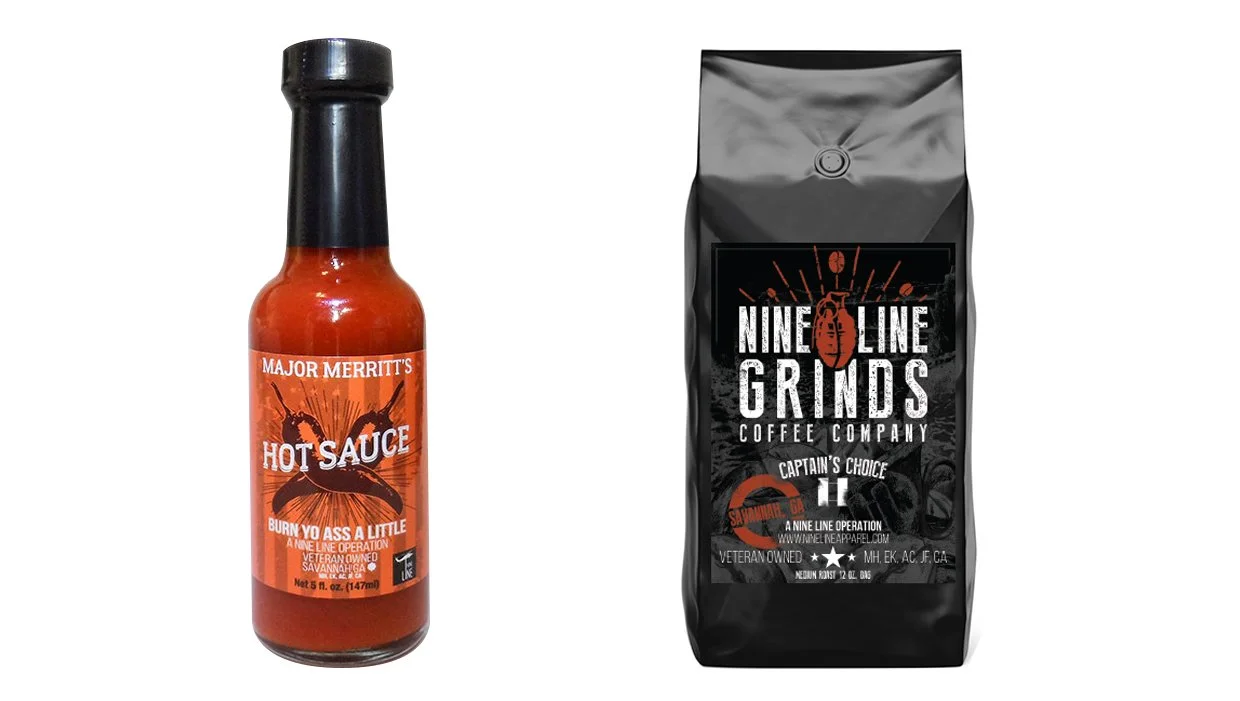 A bottle of Major Merritt's Hot Sauce and a bag of Nine Line Grinds coffee. The hot sauce bottle is orange with black cap and label, and the coffee bag is black with red and white text.
