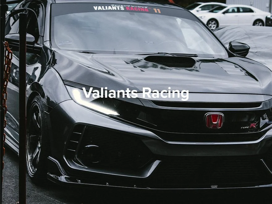 Black Honda Civic Type R racing car parked at a race event with Valiants Racing decals and a hood scoop.