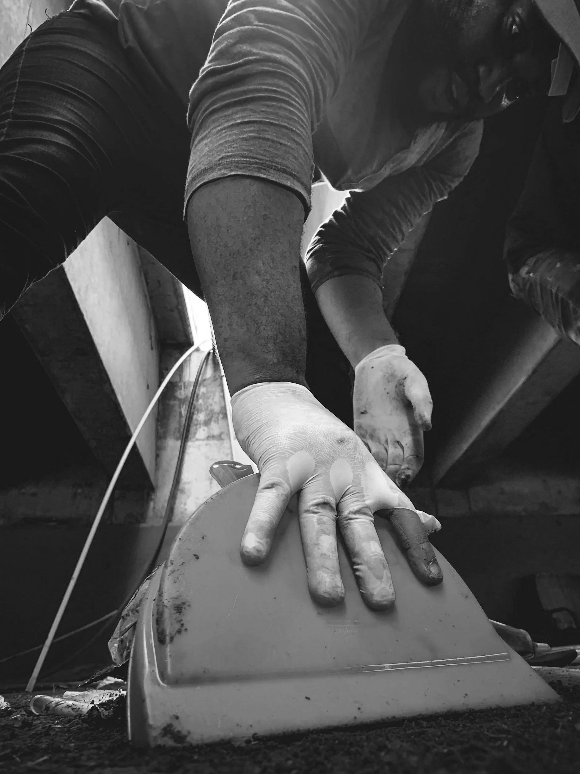 A person with glasses and gloves working on a project at a workbench, with tools and materials around.