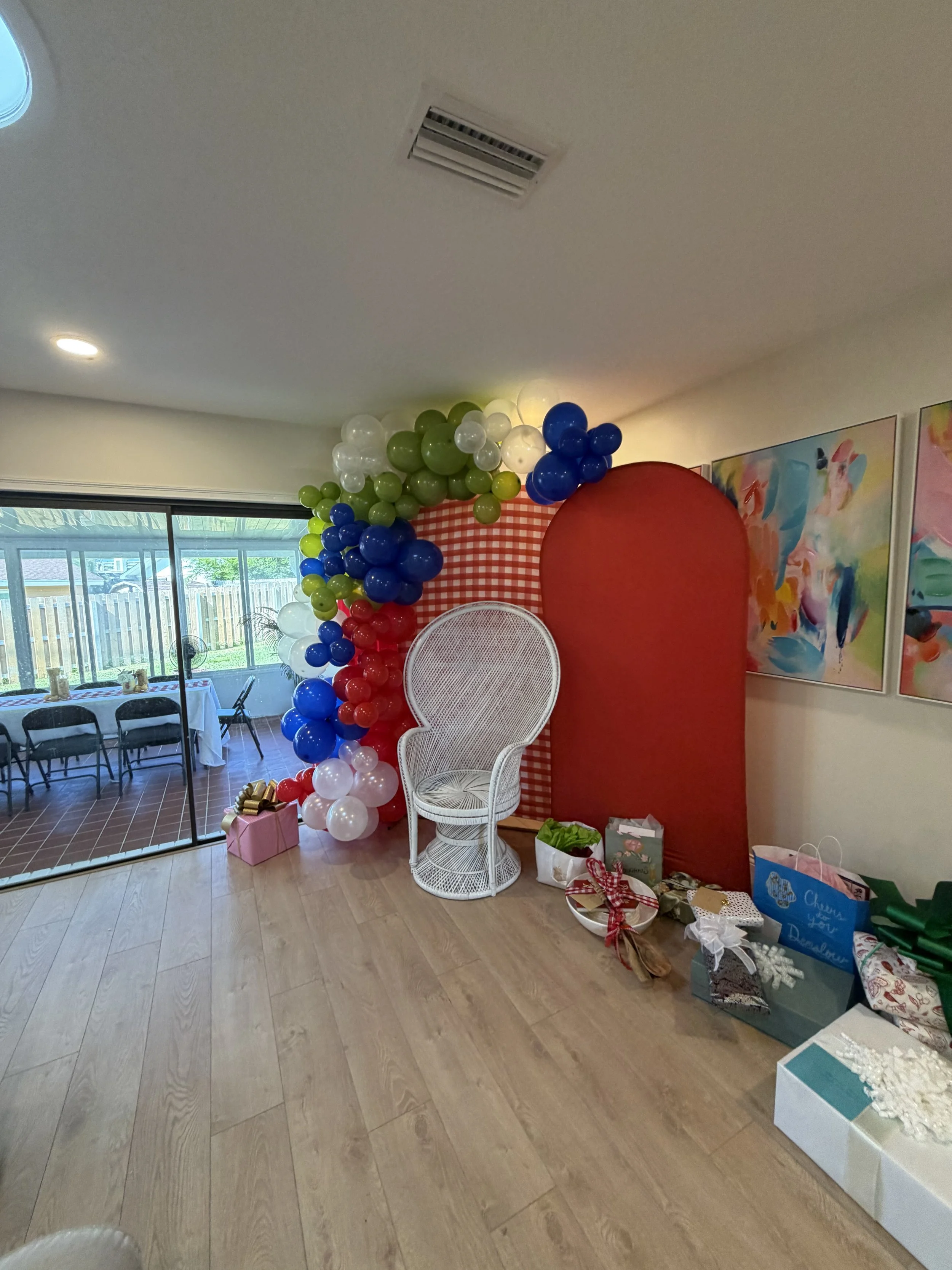 Event stylist installing a colorful red, blue, and green balloon garland for an FSU celebration.