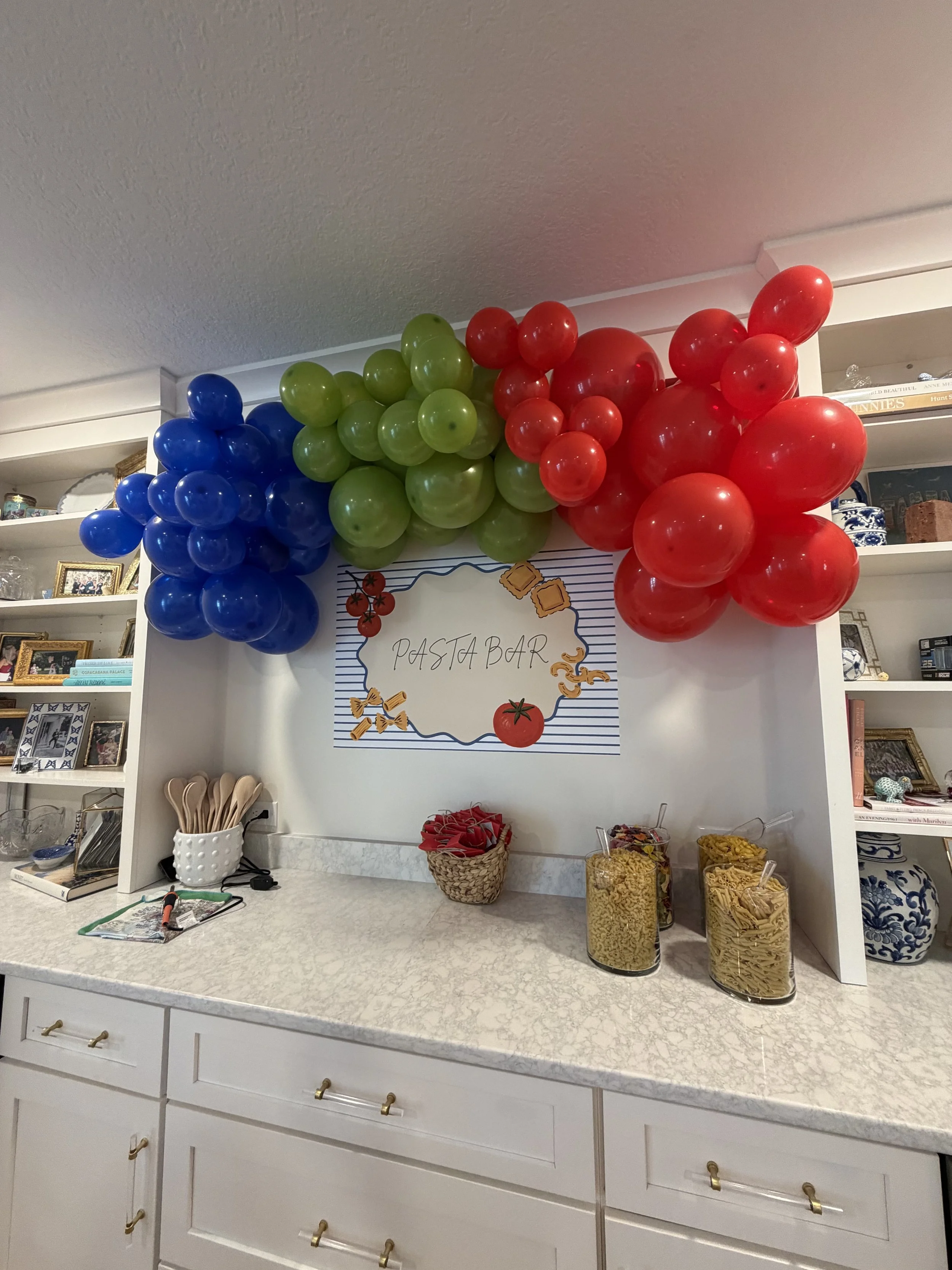 Red, blue, and green balloon garland arranged above a party display table for an FSU celebration.