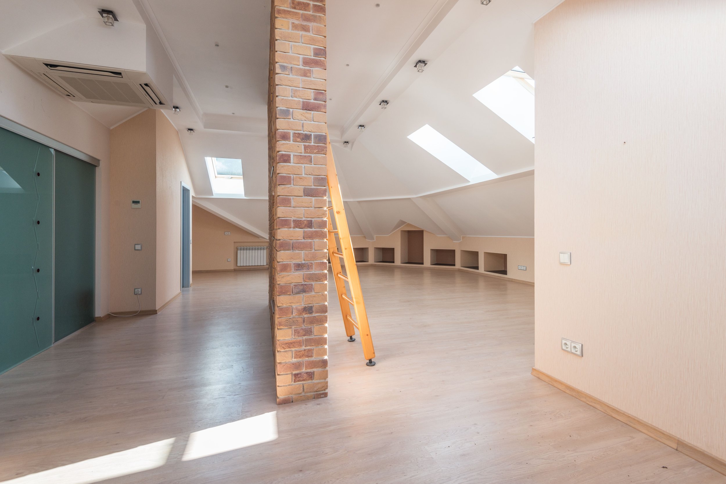 Heller renovierter Innenraum im Dachgeschoss mit Dachfenstern und Backsteinsäule