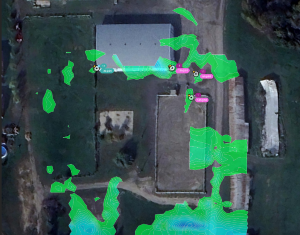 Aerial view of a property with green and blue overlay indicating surveying or mapping data, showing a house, neighboring structures, and surrounding land.