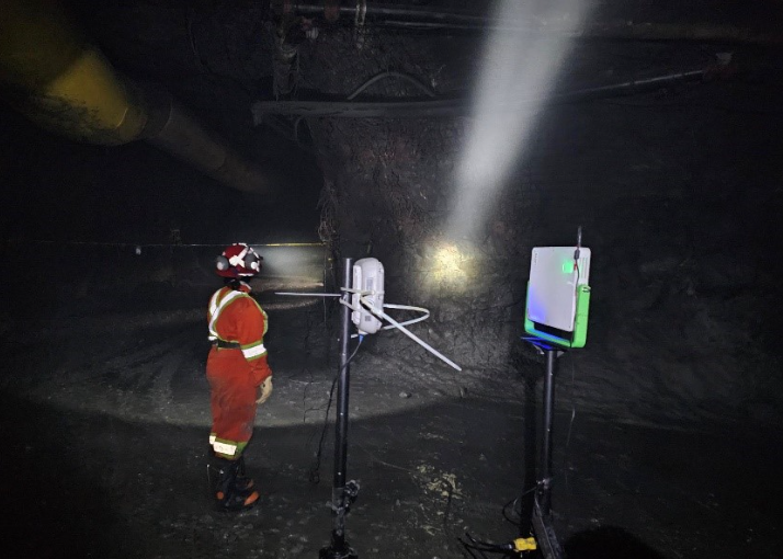A firefighter in protective gear and helmet standing inside a dark mine shaft with illuminating equipment.