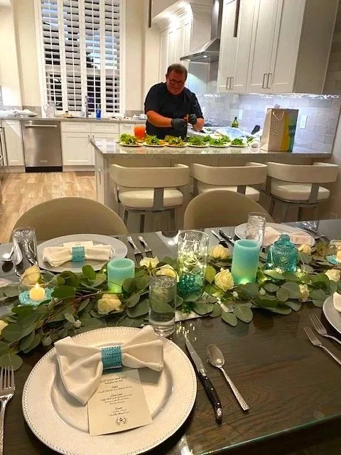 Chef Dean cooking in a modern home kitchen behind a beautifully set formal dining table for an intimate catered event