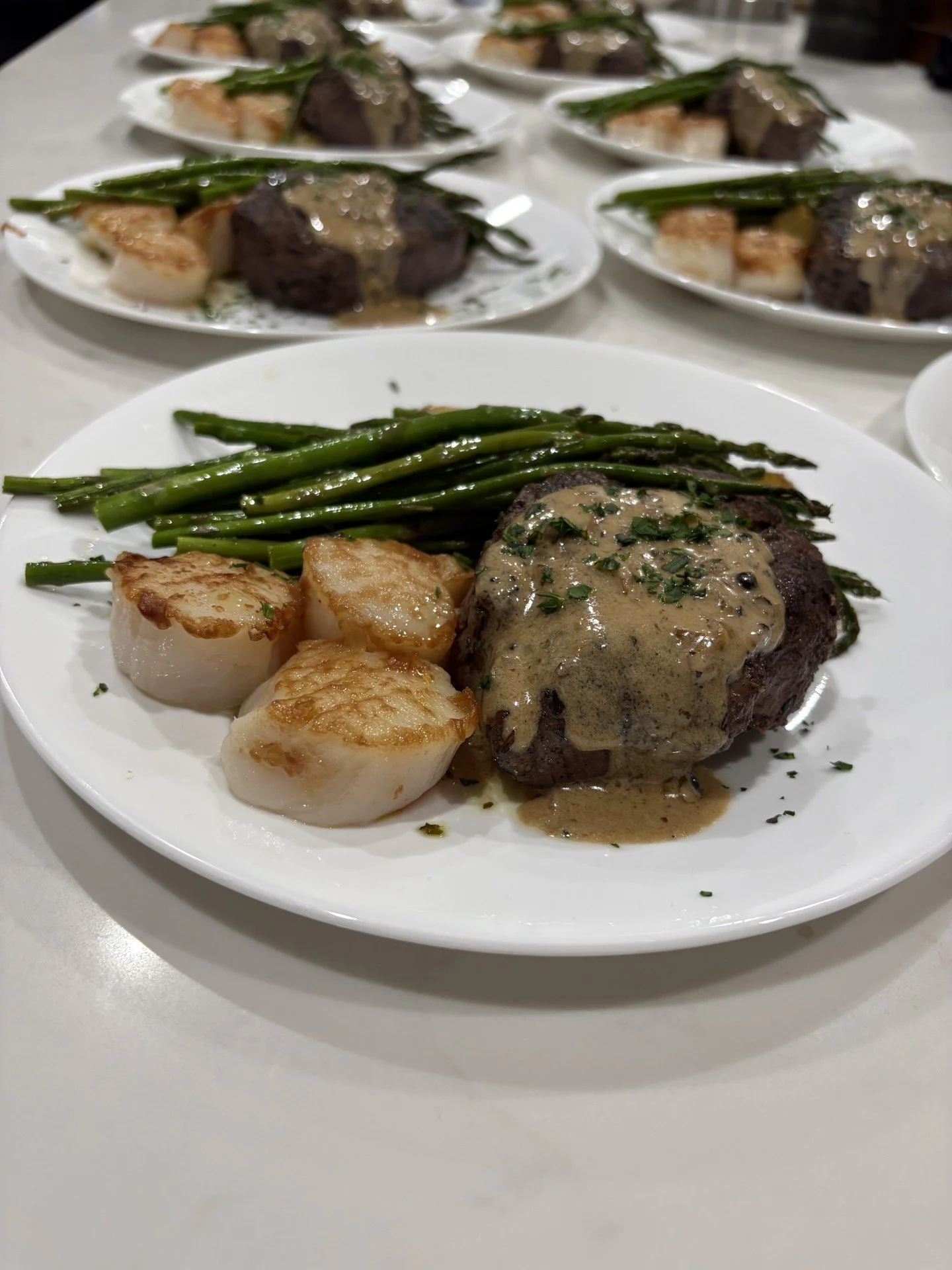 Luxury dinner plate with Filet Mignon topped with a creamy peppercorn sauce, seared Scallops and lemon asparagus in Carefree, AZ .