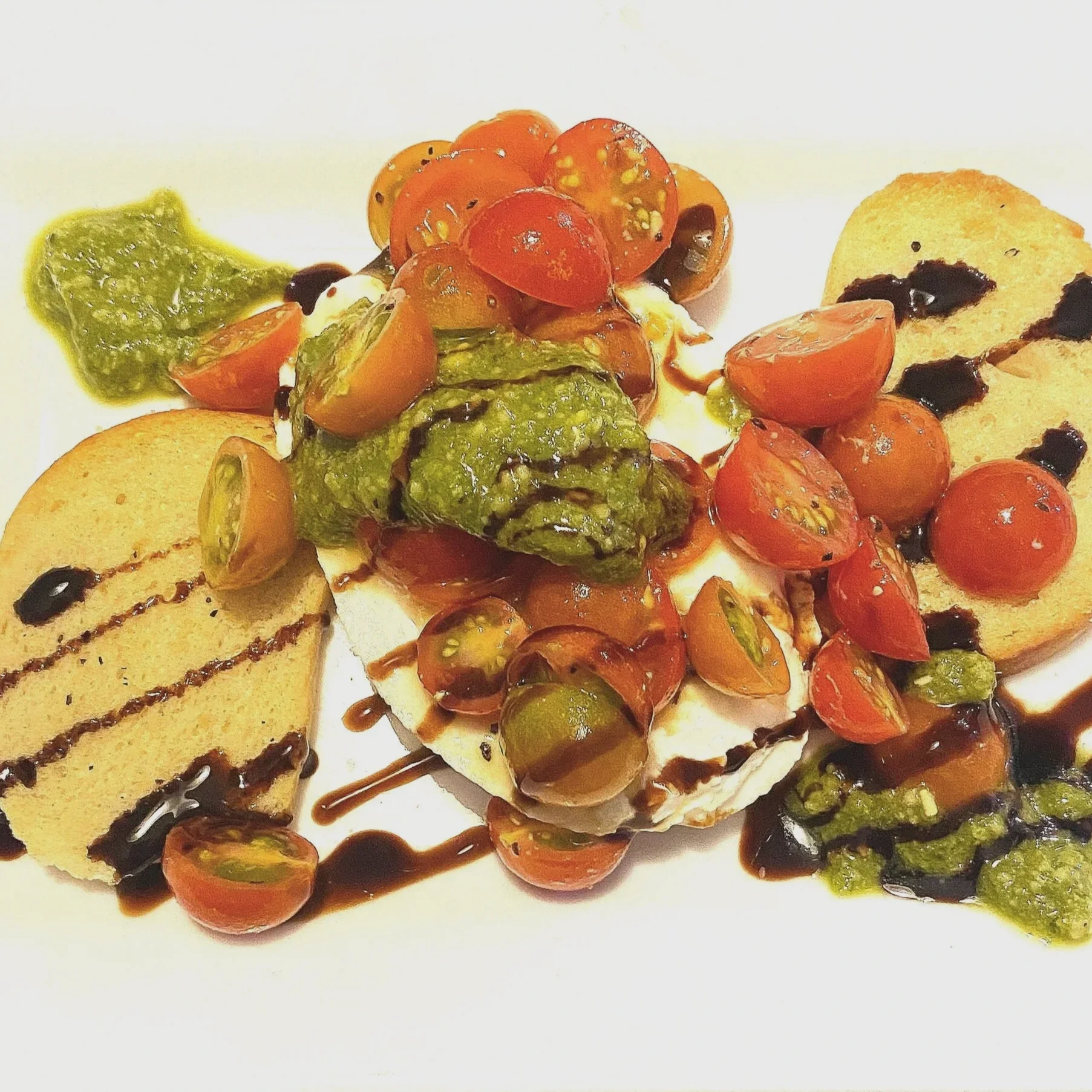 Deconstructed Caprese salad appetizer with fresh mozzarella medallions, cherry tomatoes, pesto, and balsamic glaze drizzle by Chef Dean in Phoenix.