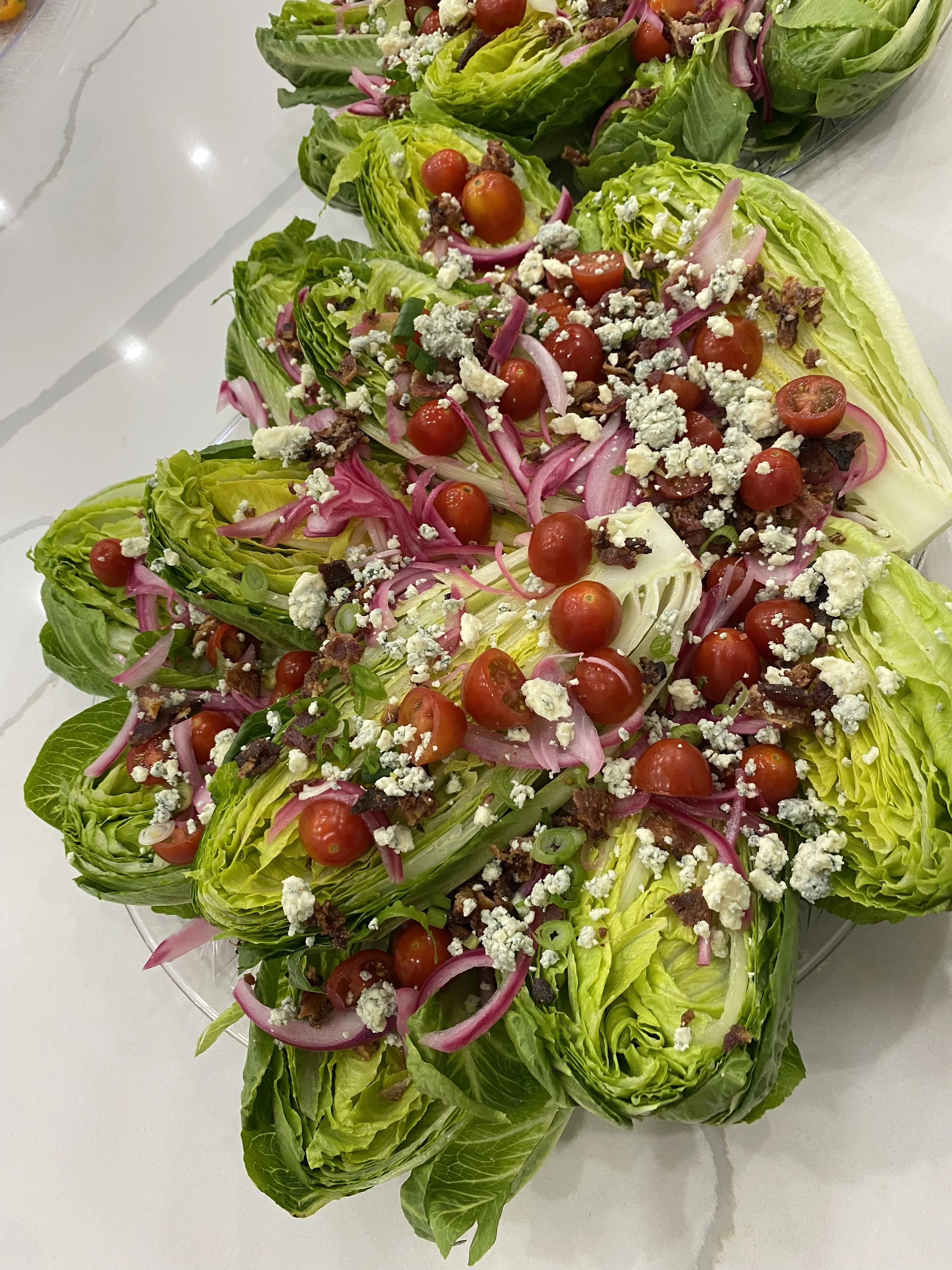 Deconstructed wedge salad with little gem lettuce, cherry tomatoes, pickled red onions and crumbled blue cheese by a luxury personal chef.