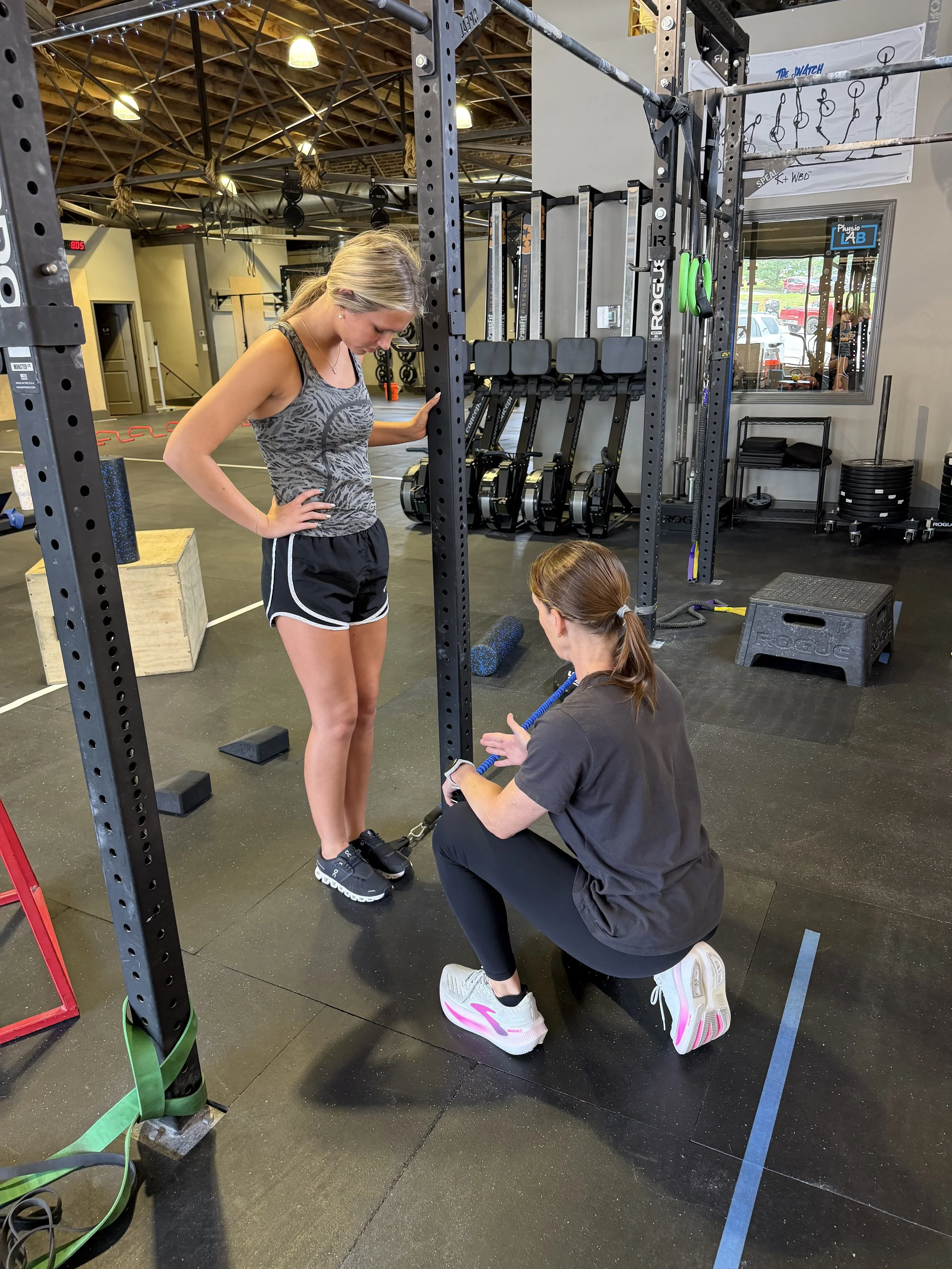 A PT working with a patient at a weight rack