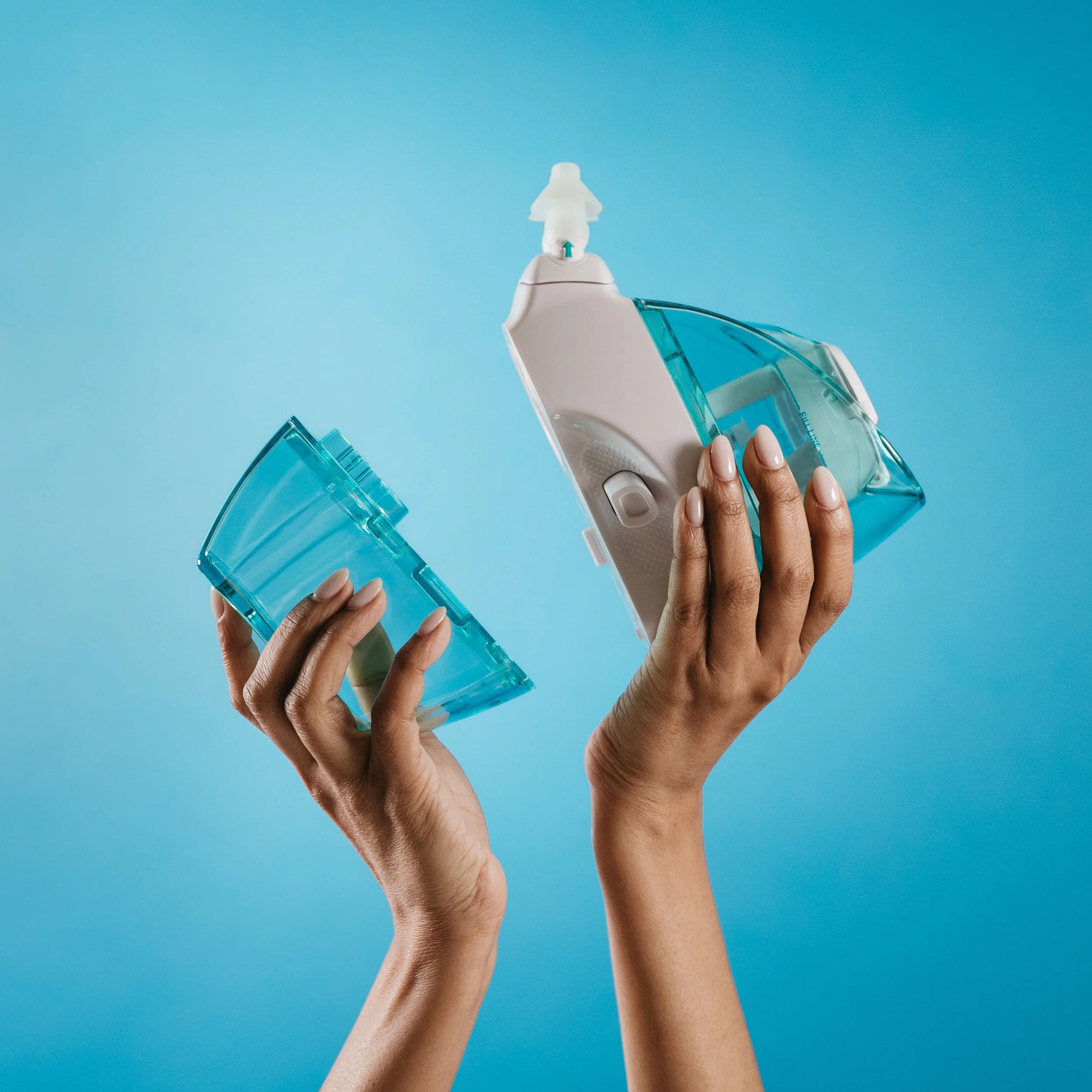 Close-up of a person holding an ultrasonic dental scaler with a blue handle and white tip against a solid blue background.