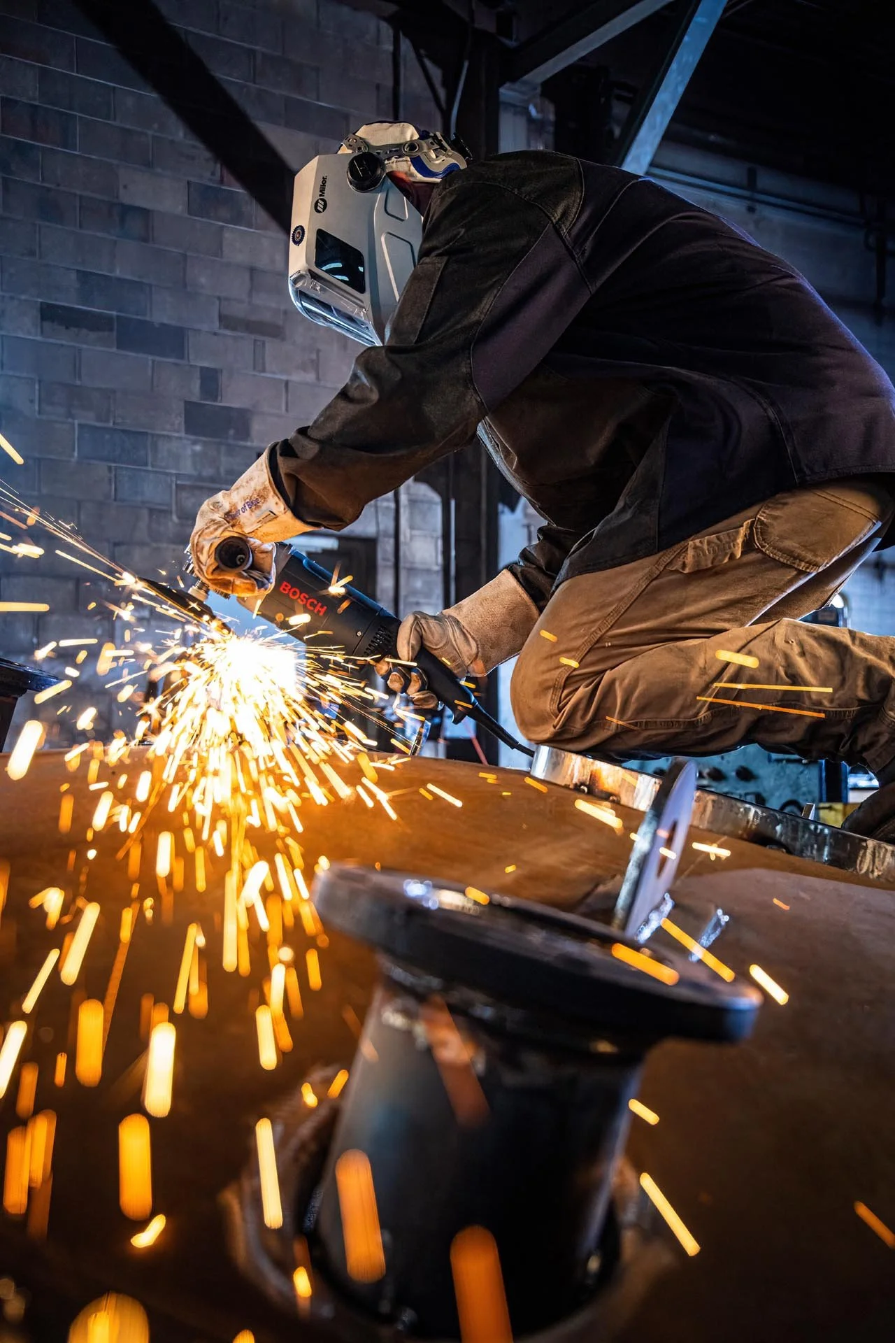 Worker welding metal with sparks flying in an industrial workshop