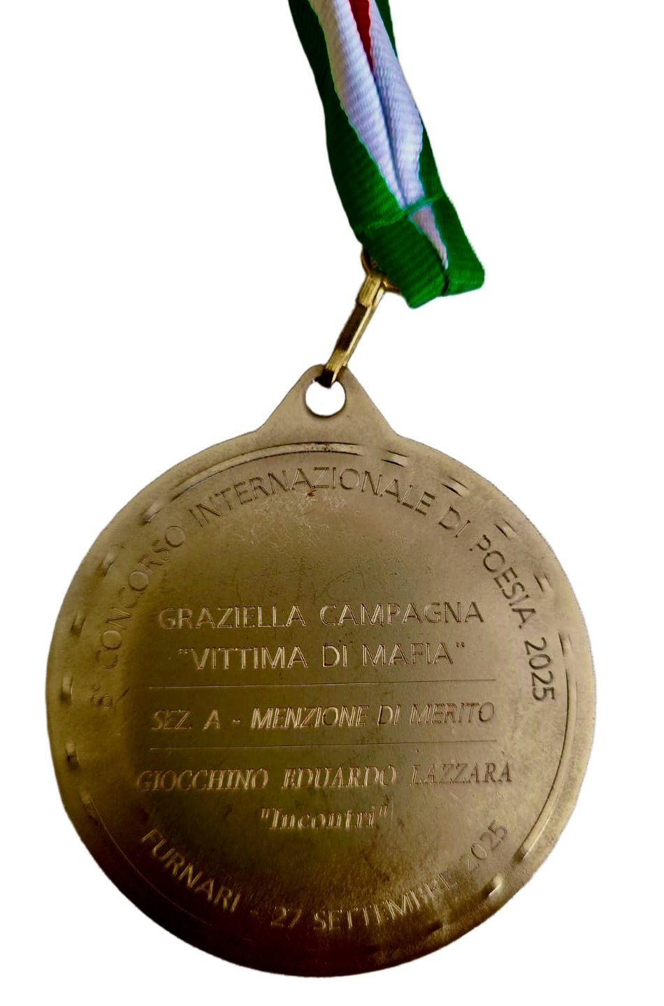 Medaglia di premio in metallo con nastro colorato, dedicata a Graziela Campagna, vittima di mafia, con dettaglio del testo scritto e data dell'evento.