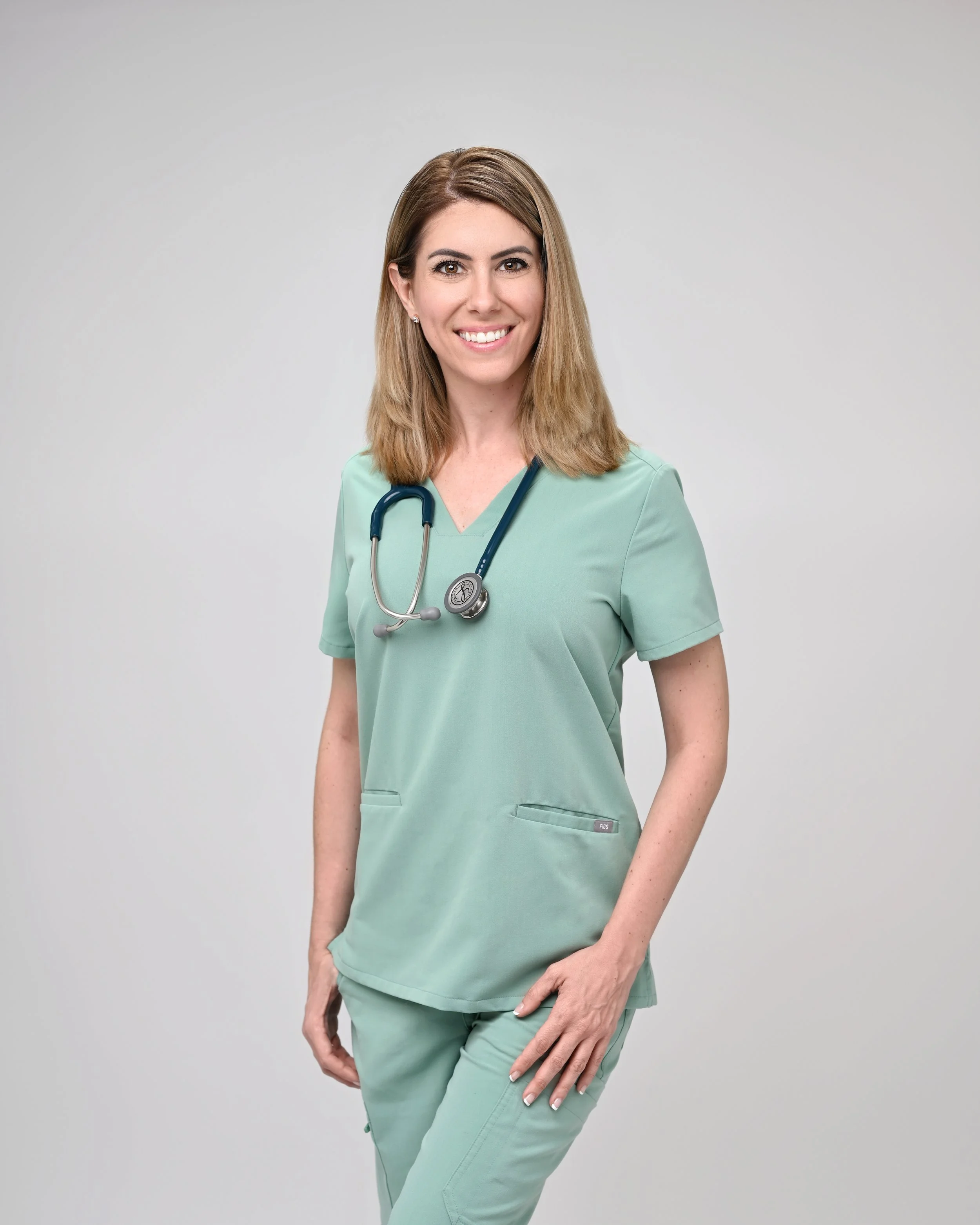 Dr. Turner, DNP wearing mint green scrubs and a stethoscope around her neck, standing against a plain white background.
