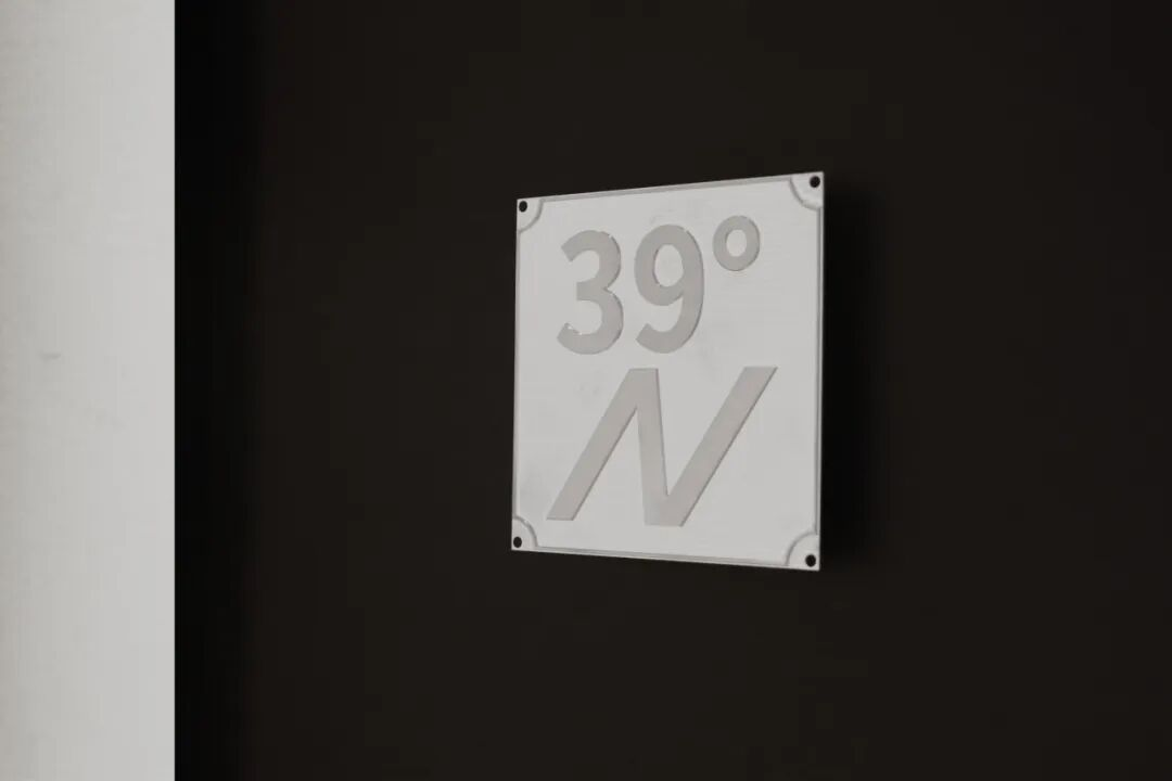 A white sign with the text "39° N" on a dark wall.