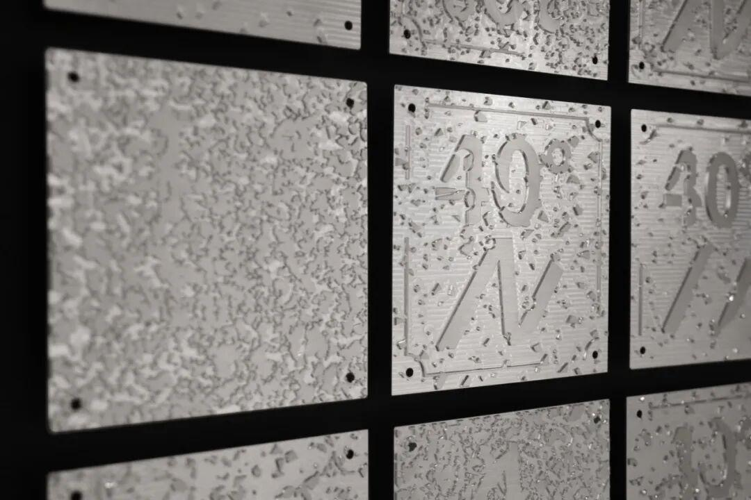 Close-up image of ice or frost-covered metallic plaques with inscriptions, mounted on a wall with black borders, showing some visible black screws.
