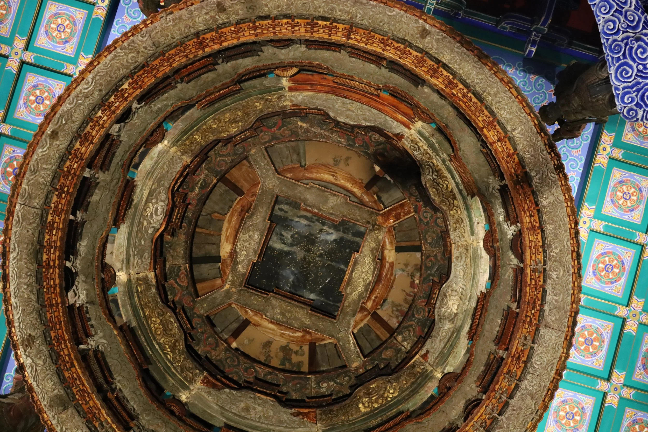 A spiral staircase with ornate details, set against sections of colorful, traditional patterned decor on the walls.