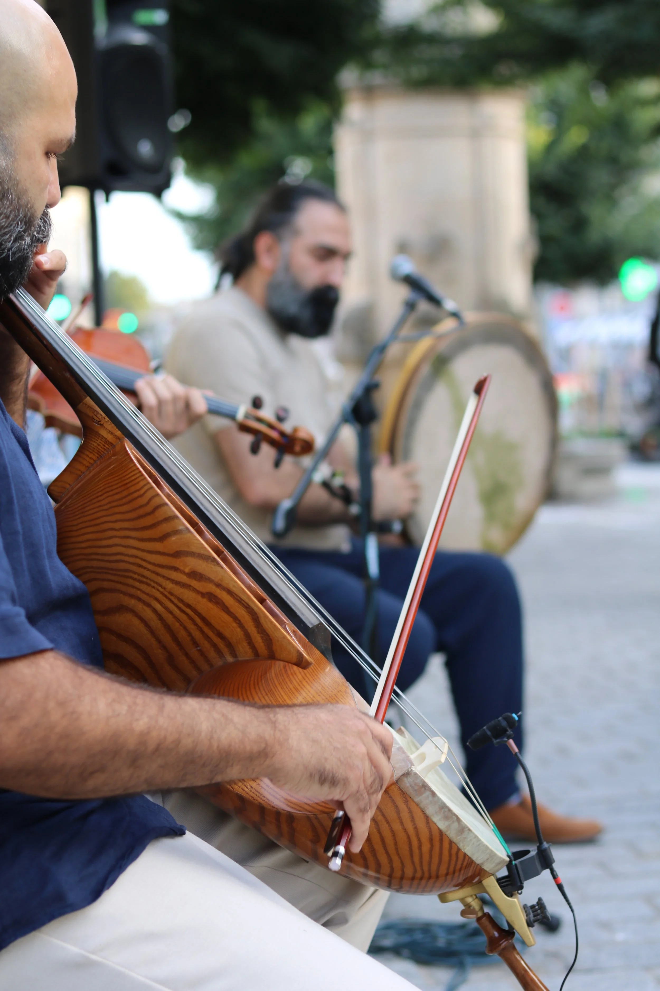 Groupe de musiciens jouant de la musique dans un espace extérieur, avec un daf (percussion) et un geychak (instrument rare à cordes) en première position.