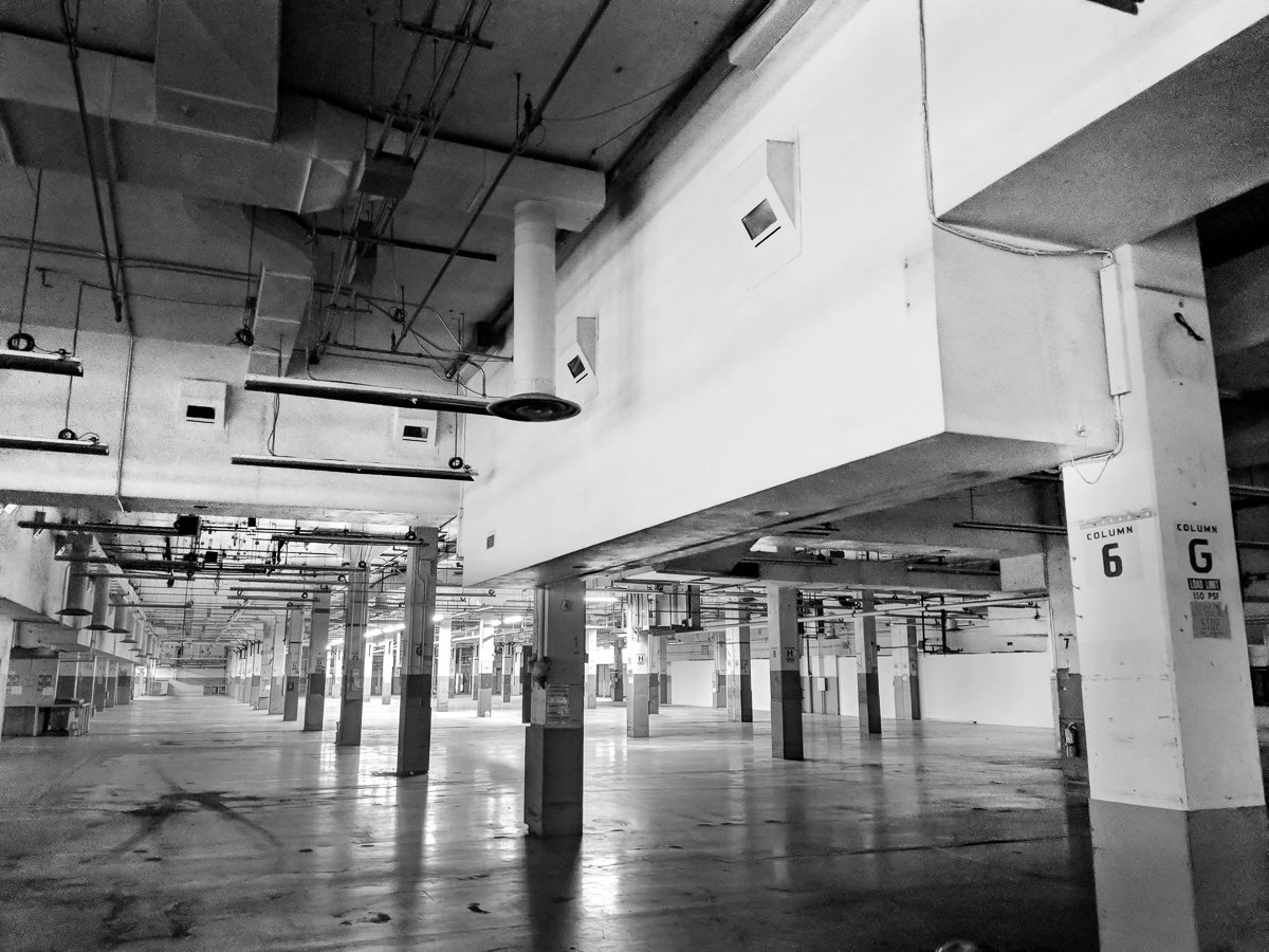 Empty parking garage with concrete columns and pipes, no vehicles or people visible.