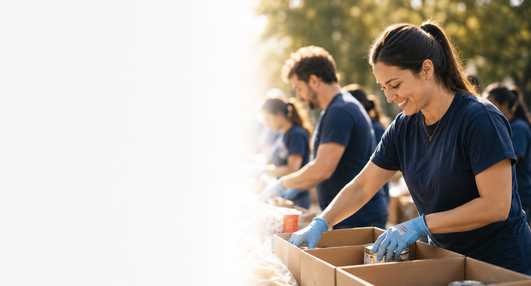 People volunteering outdoors, packing canned food into boxes during a charitable event.