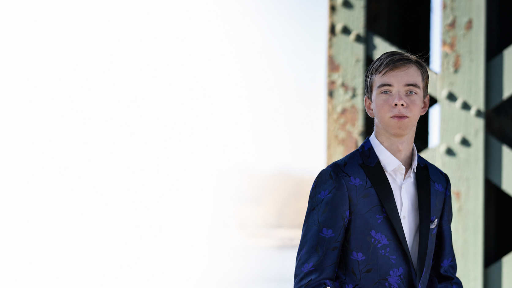 Pierce Jackson in a blue floral blazer and white shirt standing against a textured industrial background.