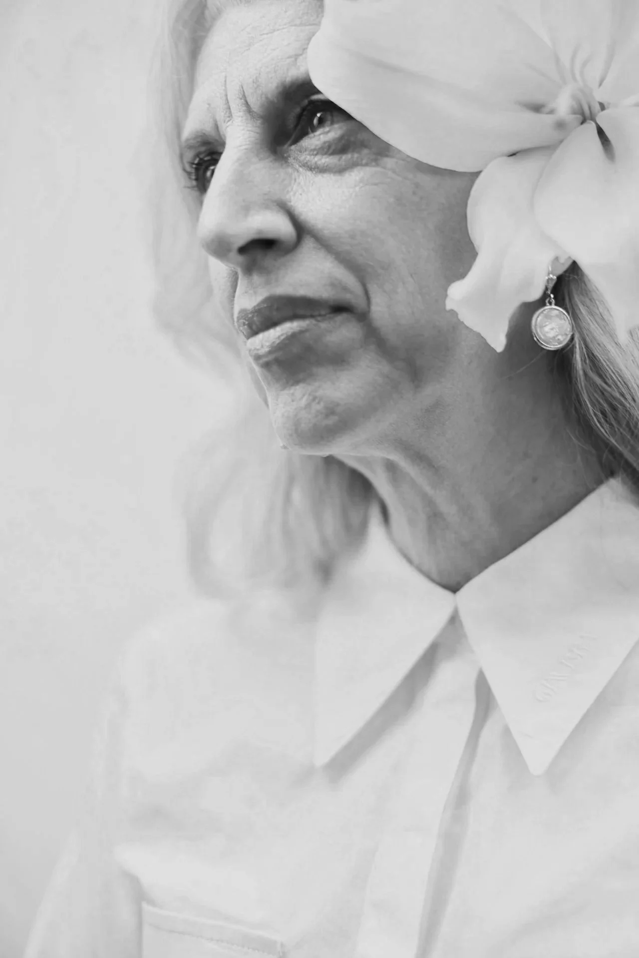 Black-and-white portrait of an older woman wearing a flower in her hair, representing healthy aging, confidence, and women's wellness at every stage of life.