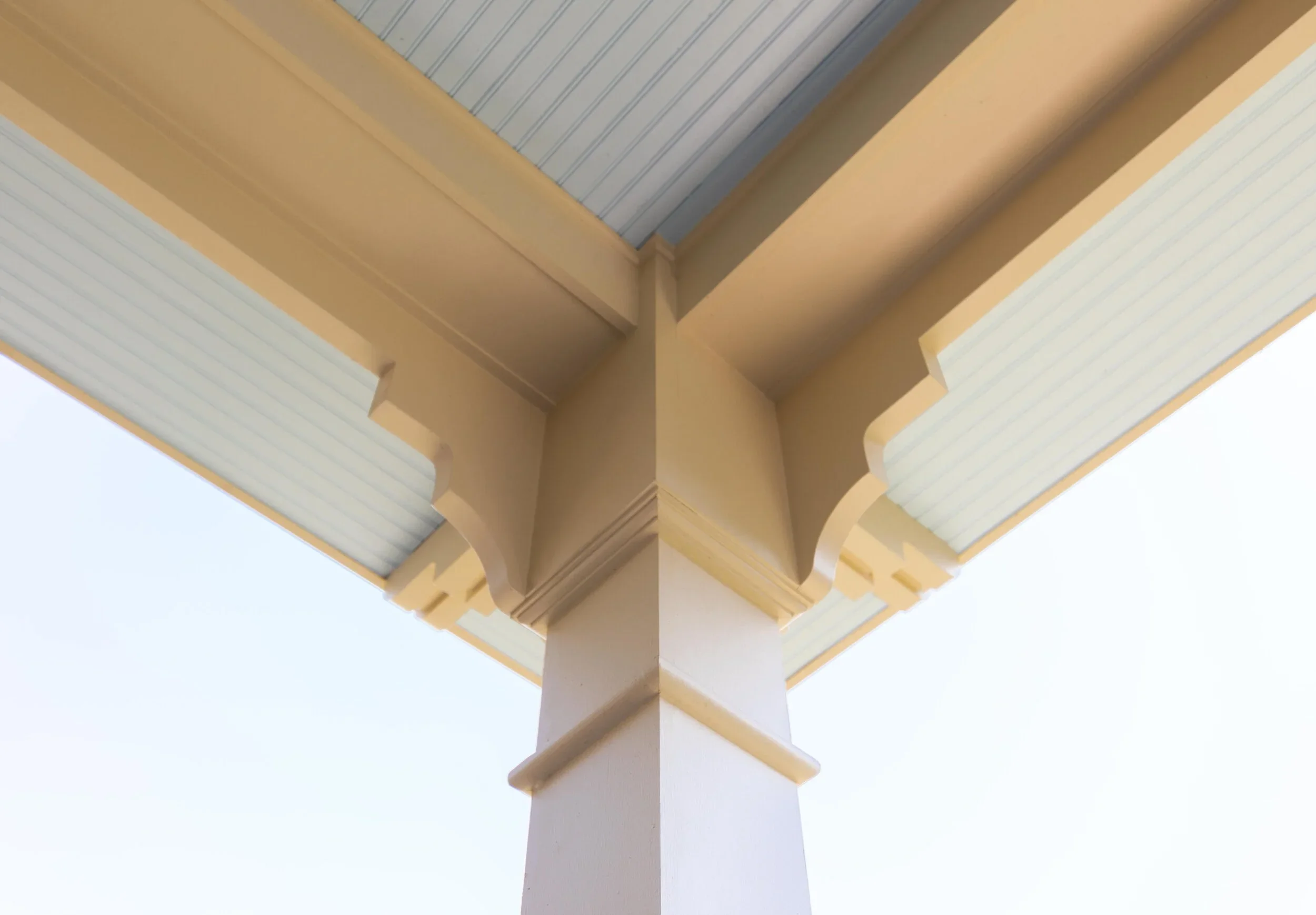 A close-up view of the underside of a beige-colored ceiling with architectural molding and design details, viewed from directly below.