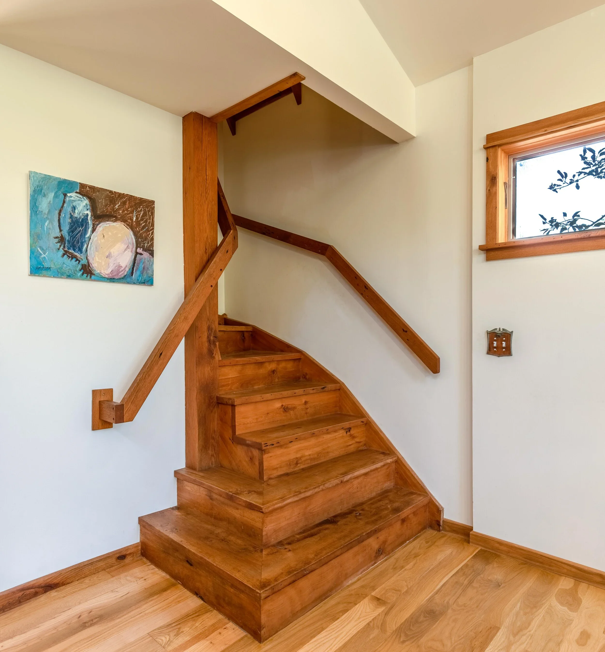 Wooden staircase with a small section of a wall painting and a window with a wooden frame.