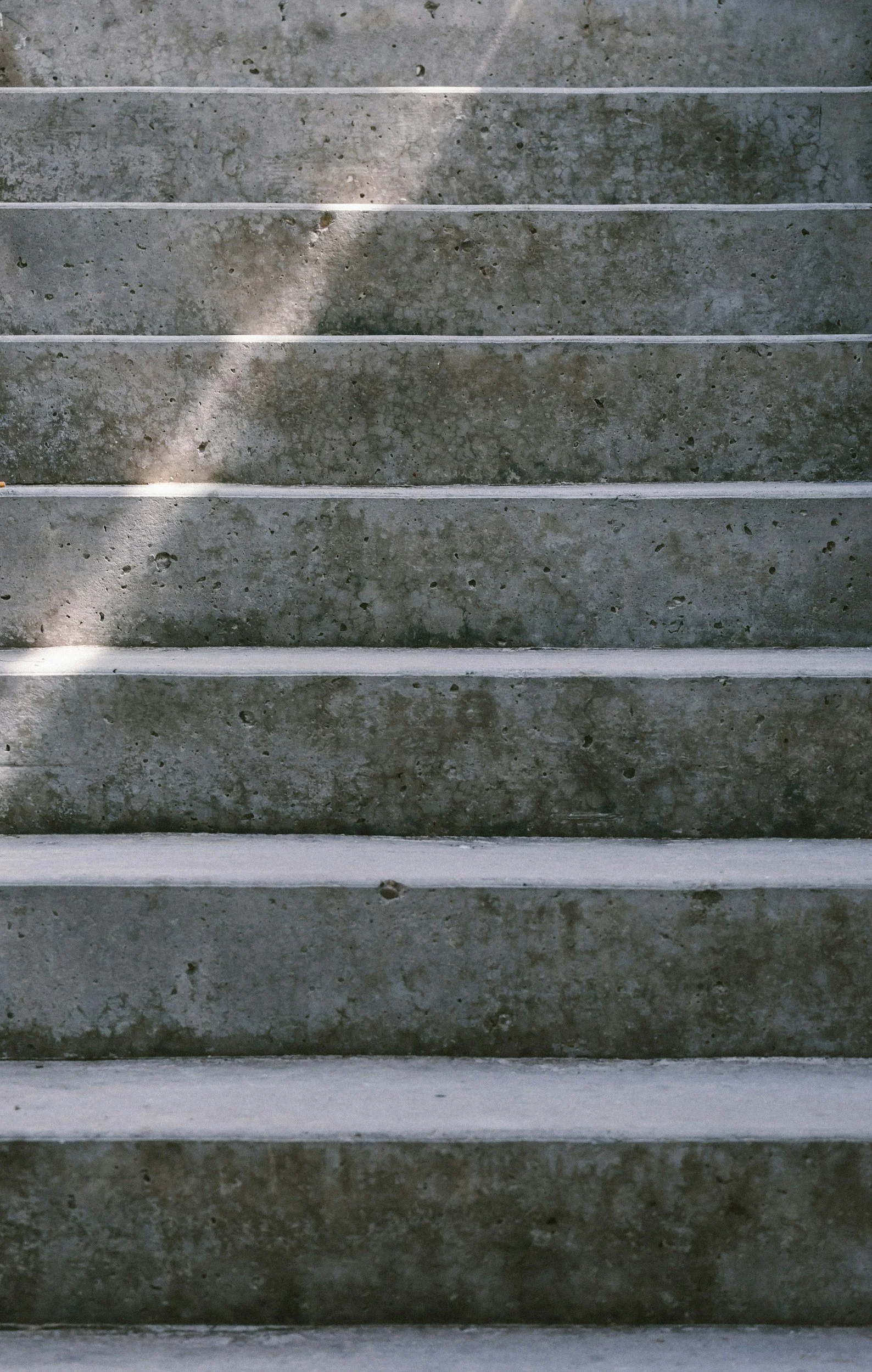 Concrete stairs with white edging and shadows cast across them.