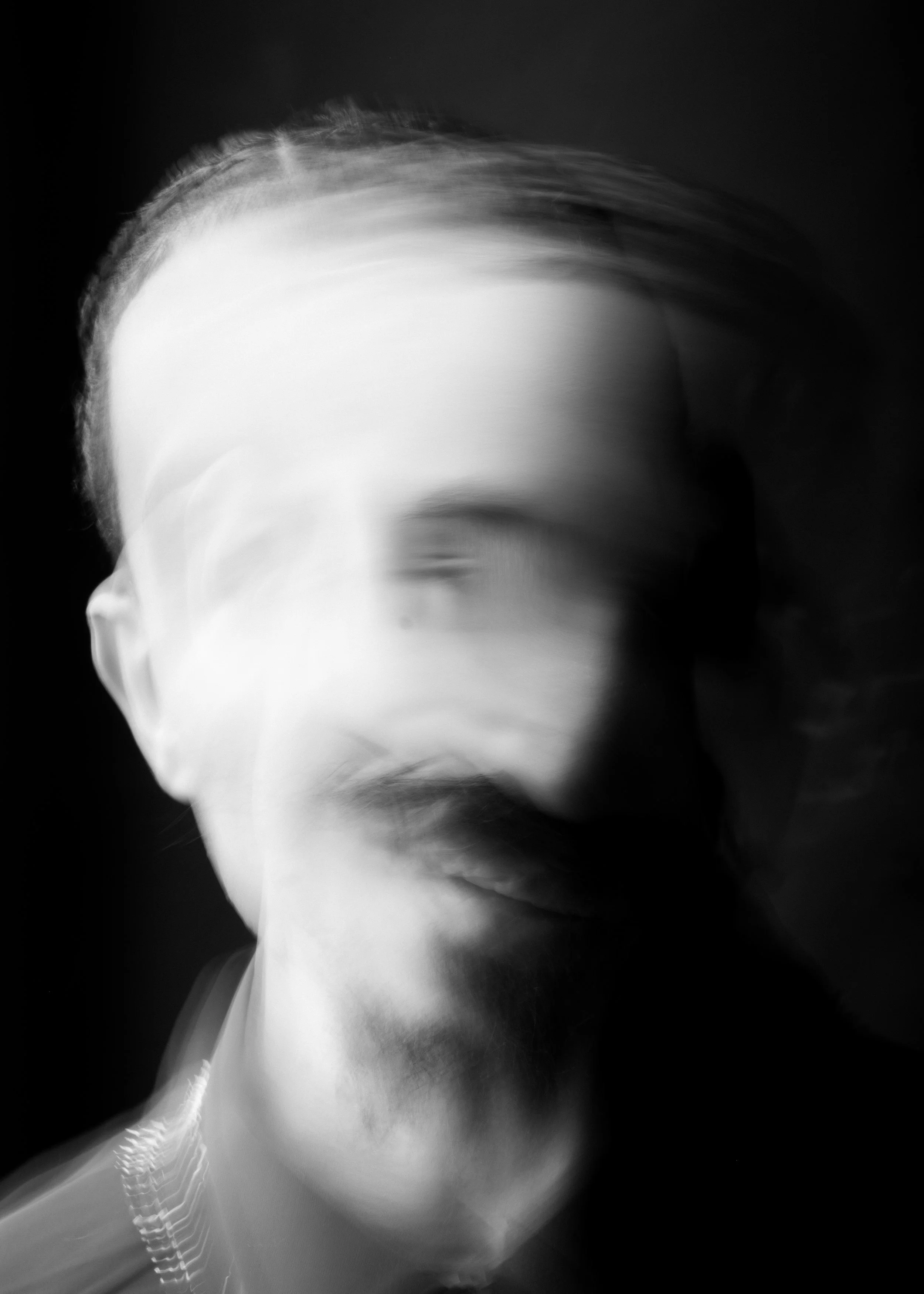 Abstract black and white blurred image of a person with gazing eyes, partially visible face, and stylized hair.