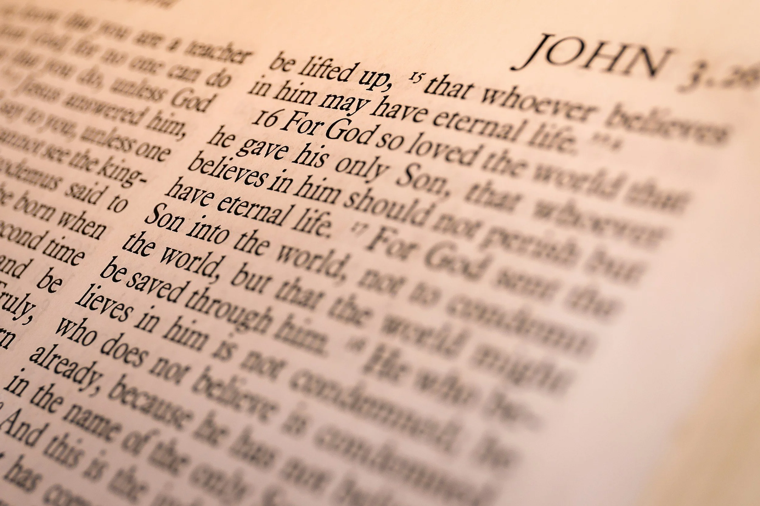 Close-up of a page in a book, showing a section of text with the word 'JOHN' at the top, and the text is slightly blurred.