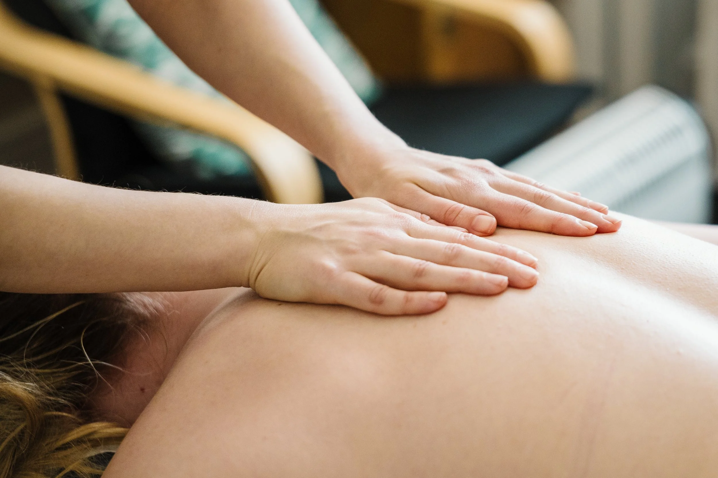 Person receiving a back massage while lying face down, with hands pressing along the spine.
