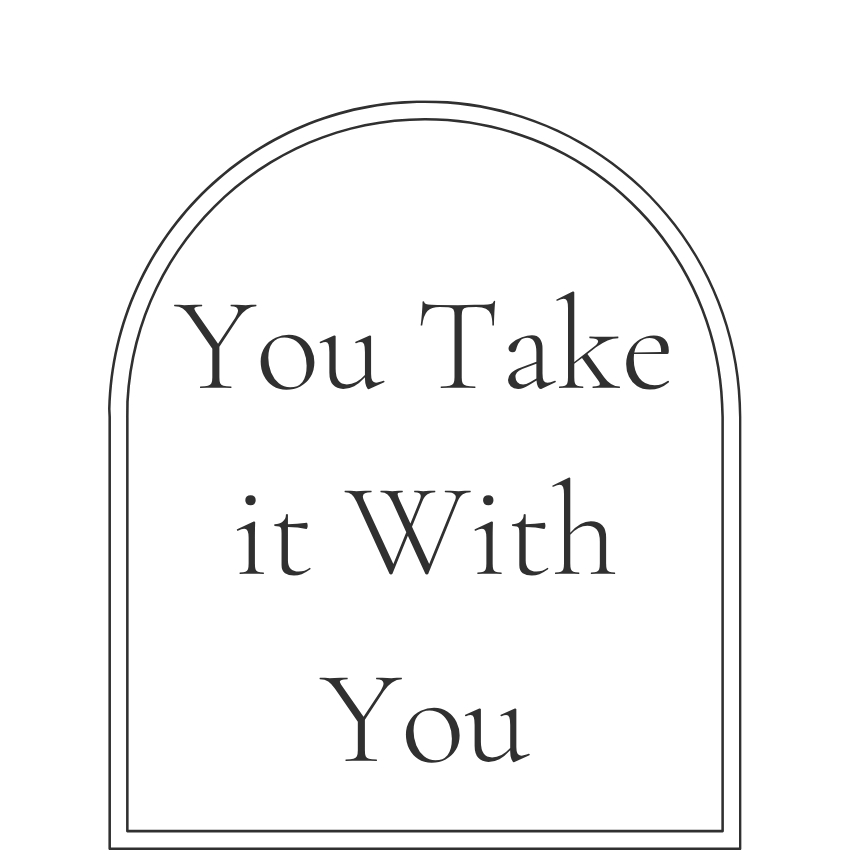 A black tombstone-shaped sign with the quote "You Take it With You" written in the center.