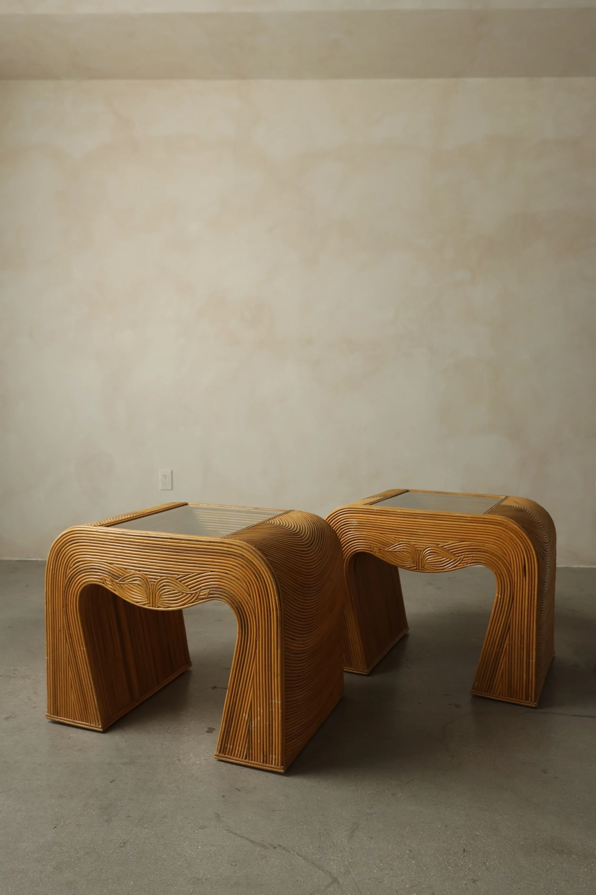 Three wooden chairs with curved and slatted designs on a gray floor in front of a plain beige wall.