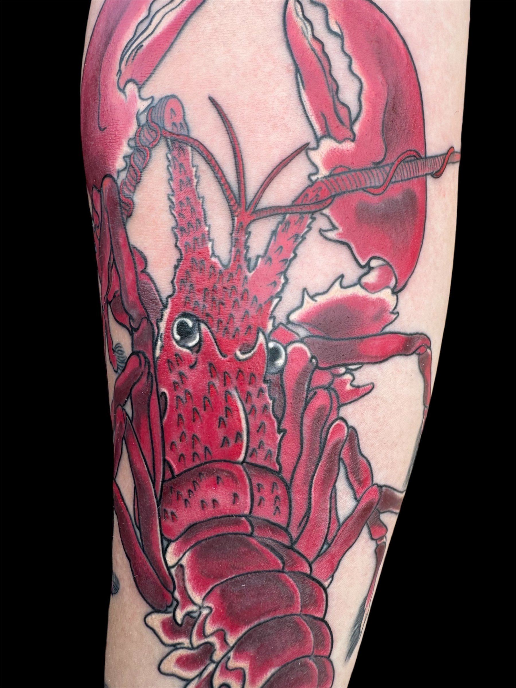 Tattoo of a red fish with black outlines and shading on a person's arm.