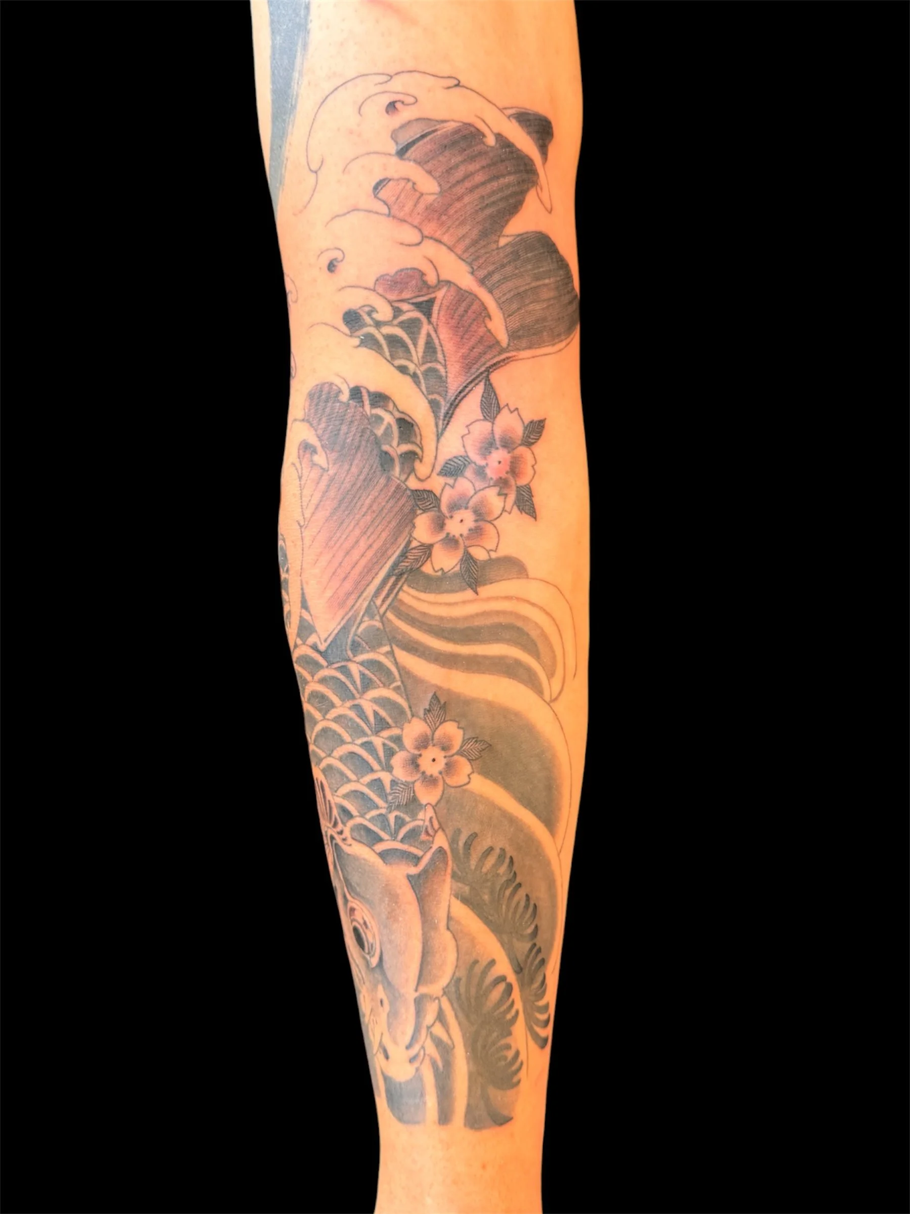 Tattoo of a dragon flowing down a person's arm with floral accents.