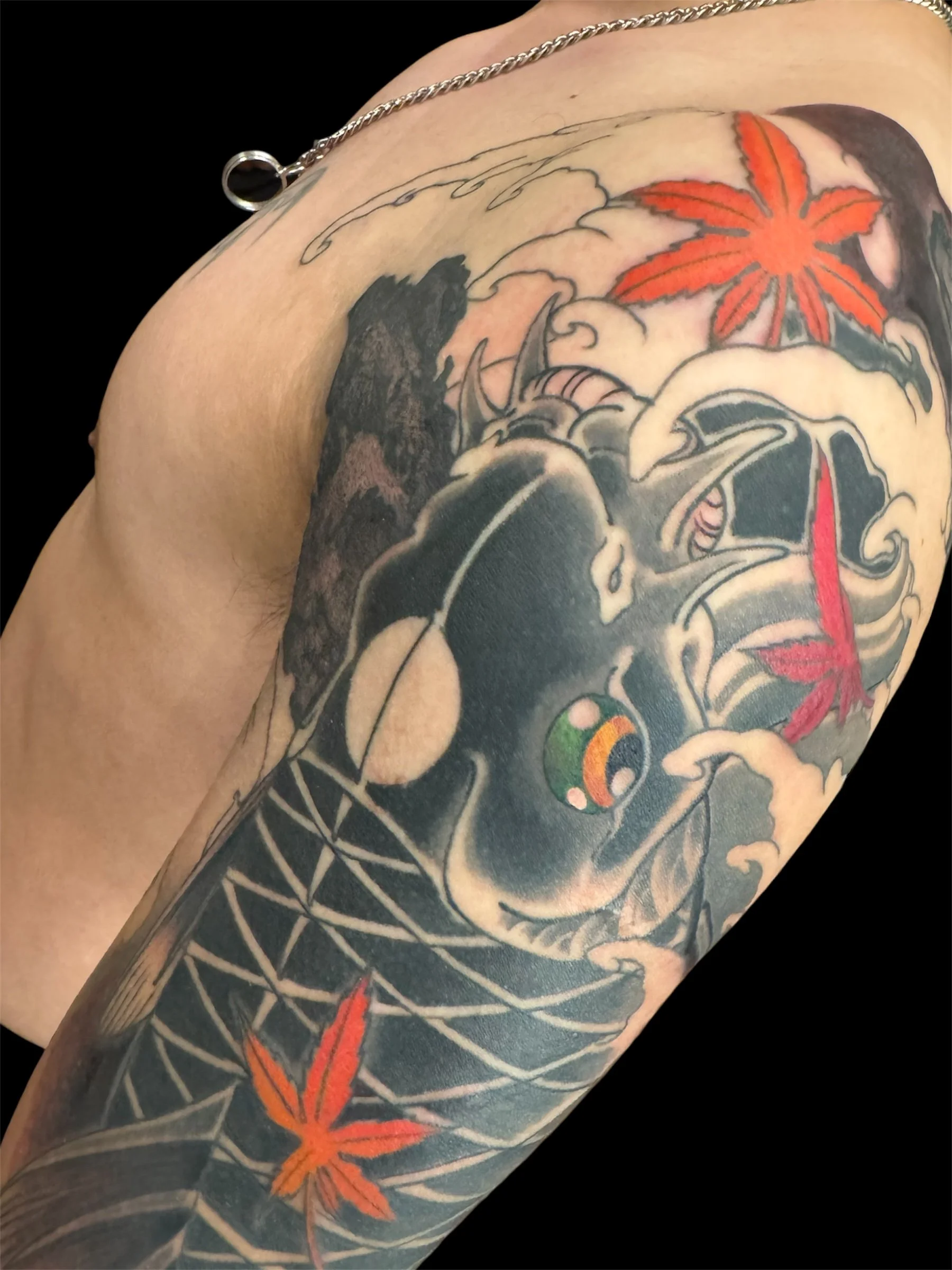 Tattoo sleeve featuring a red maple leaf, a black and gray dragon, a koi fish, and waves.