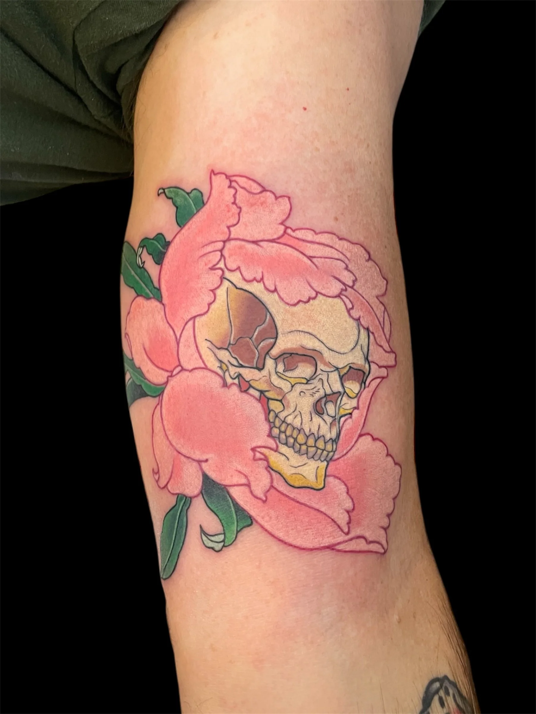 Tattoo of a pink flower with a skull inside it on a person's arm.