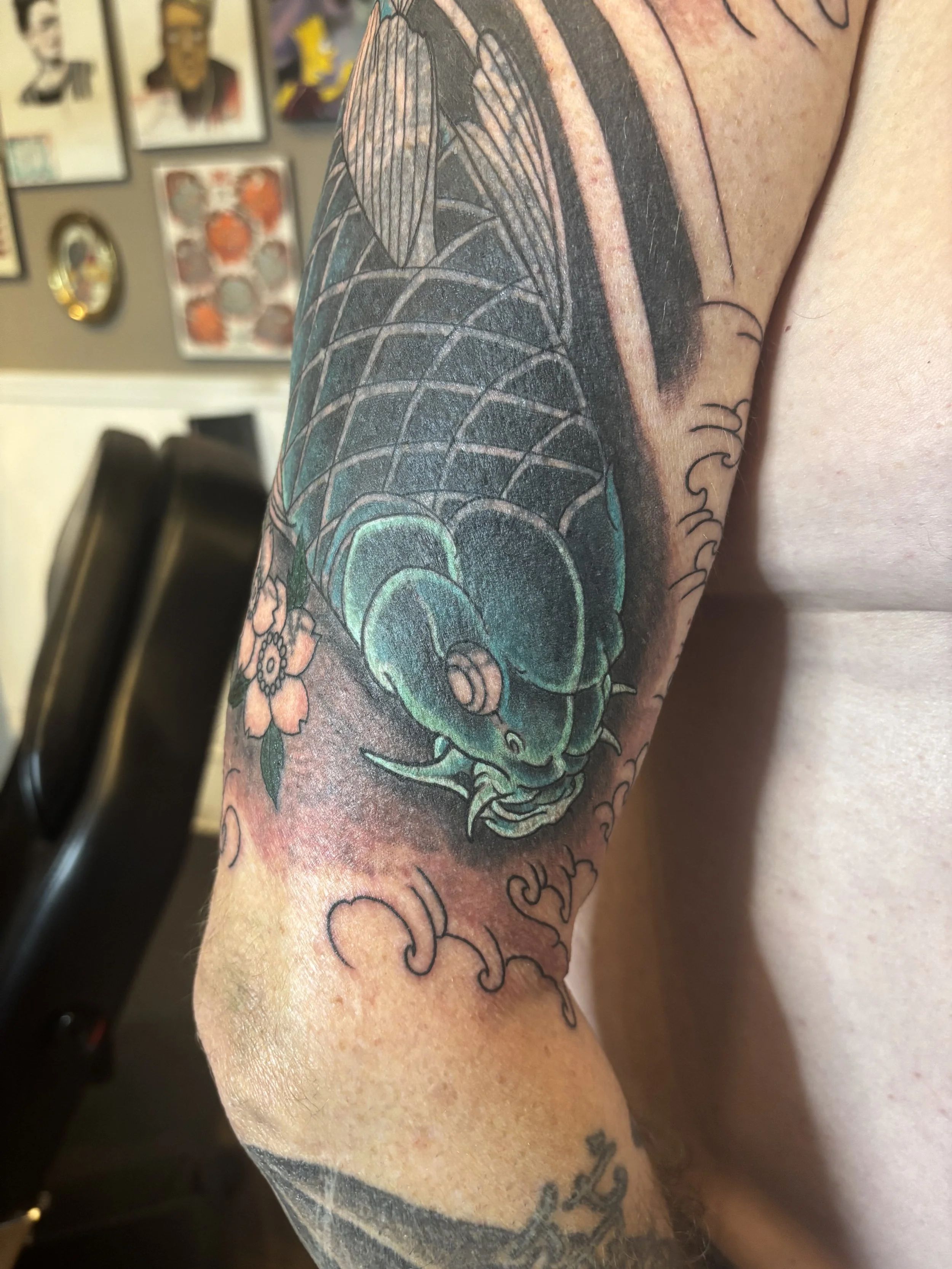 Tattoo of a bee with colorful wings and floral elements on a person's arm.