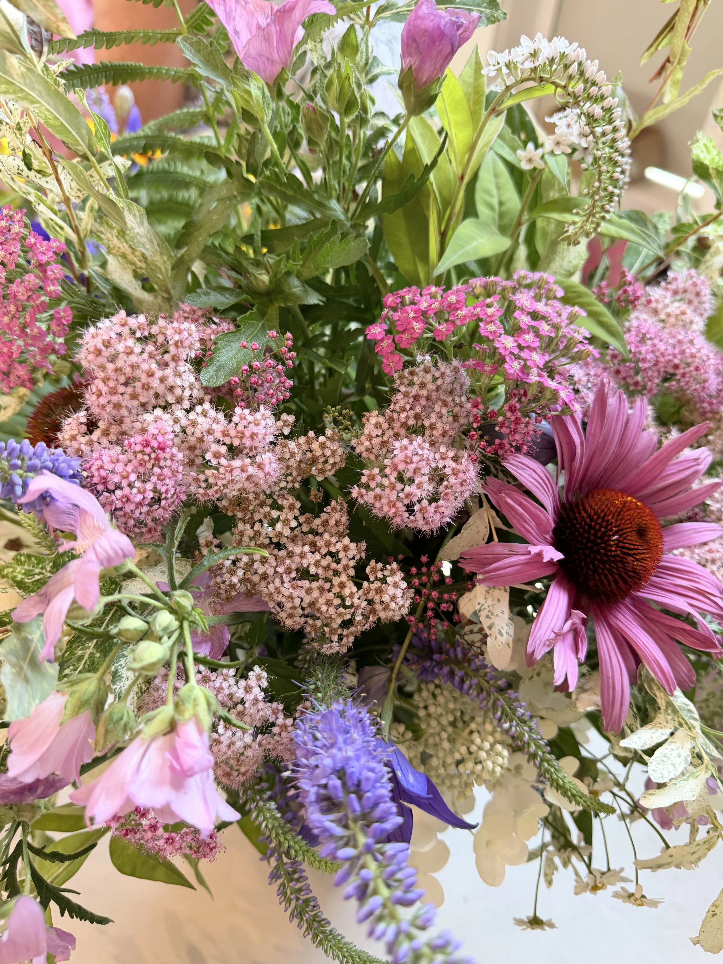 A vibrant bouquet of various colorful flowers including pink, purple, and white blossoms with lush green foliage.