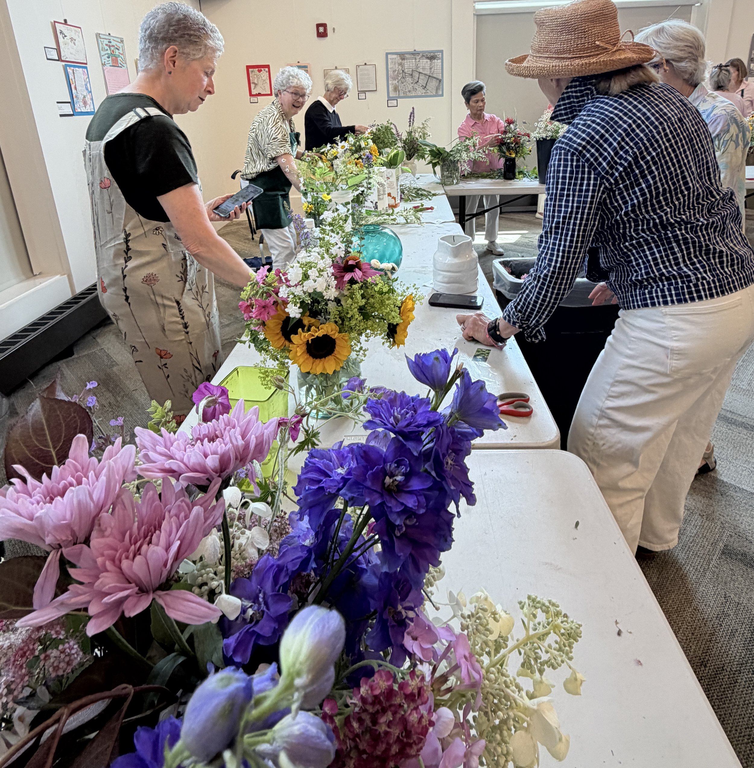 People arranging and enjoying a display of colorful flowers at an indoor art or flower exhibition.