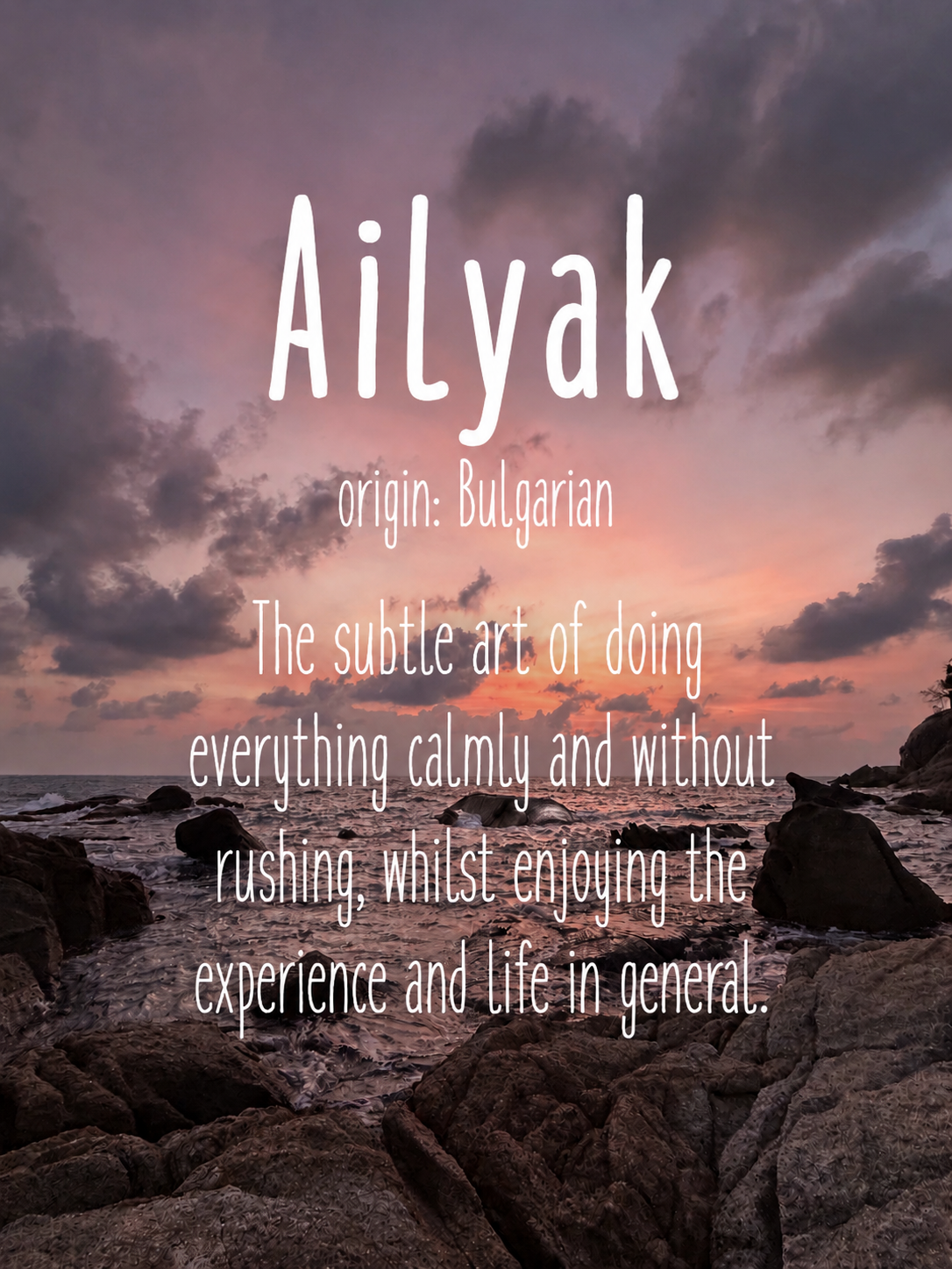 A sunset over a rocky beach with pink and purple clouds in the sky, featuring an overlaid quote about the Bulgarian origin of the word 'Ailyak' and its subtle art of doing everything calmly.