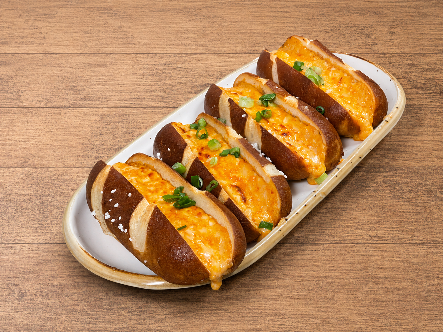 Baked cheese-stuffed mushrooms topped with green onions on a white ceramic platter.