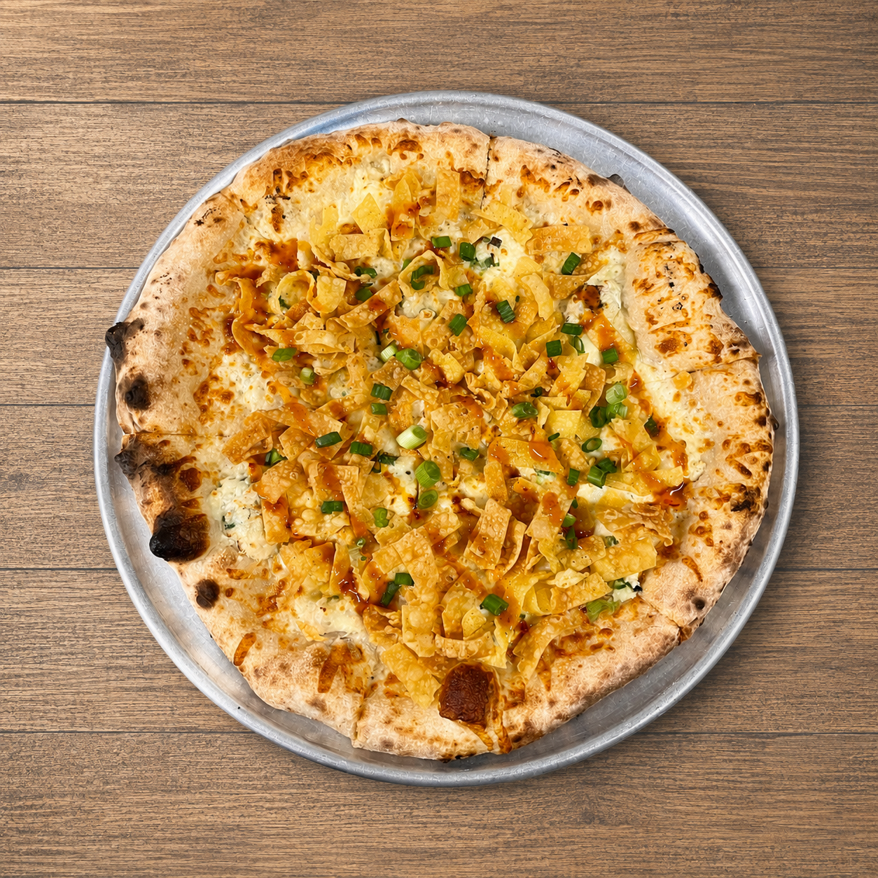 Cheese pizza topped with chopped green onions on a round metal tray, viewed from above.